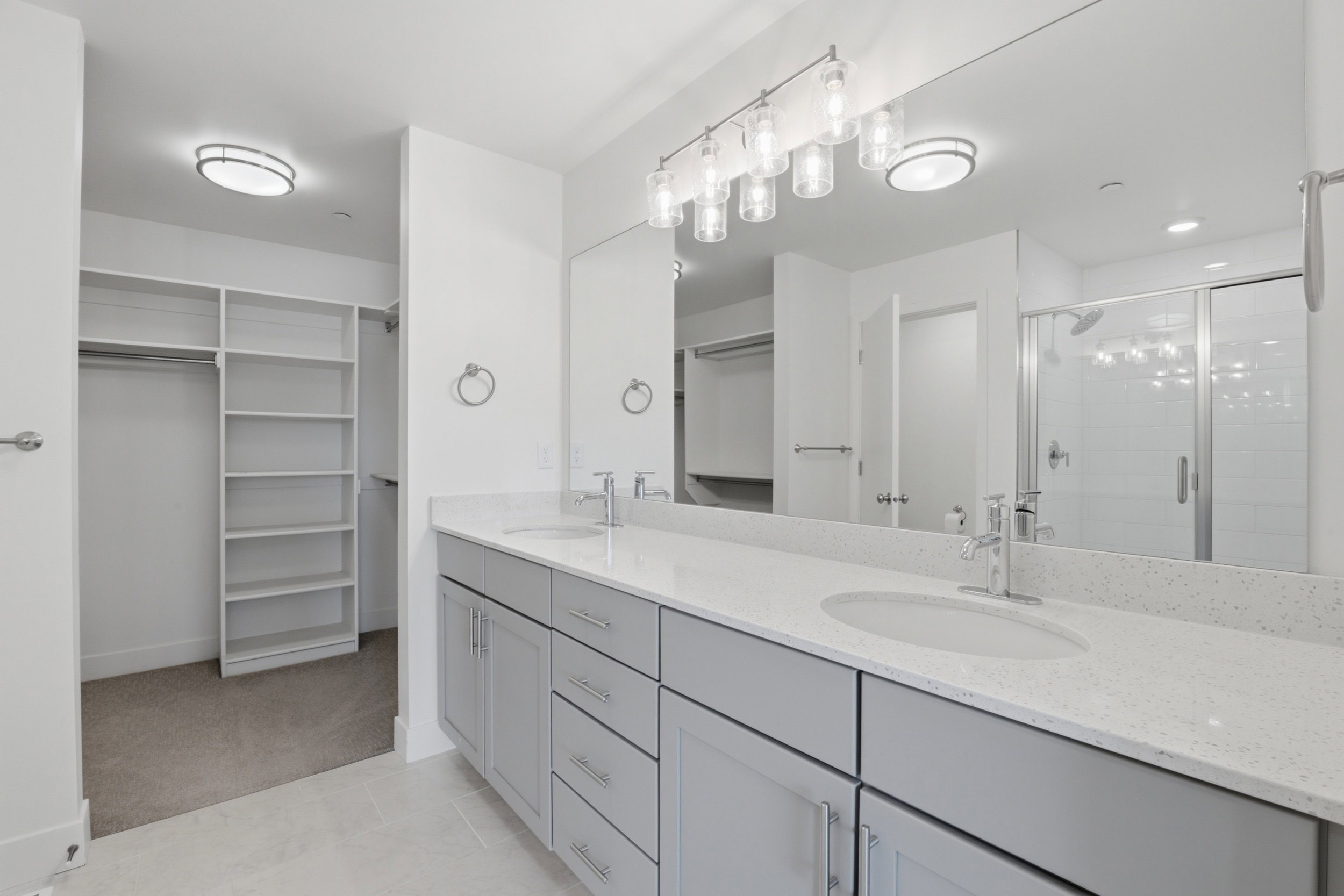 Primary ensuite bathroom with double vanity, grey cabinetry and white quartz countertops