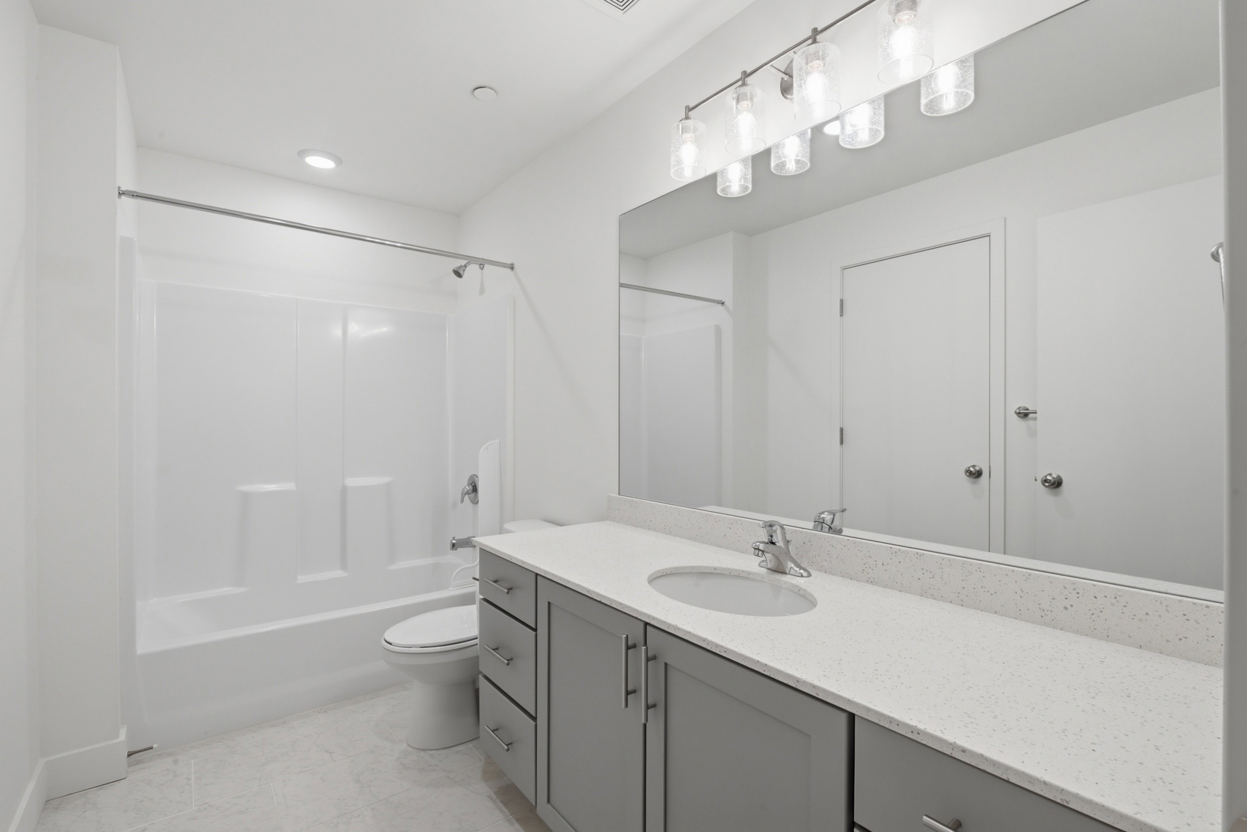 Second ensuite bathroom featuring a single vanity with white quartz countertops and a large mirror