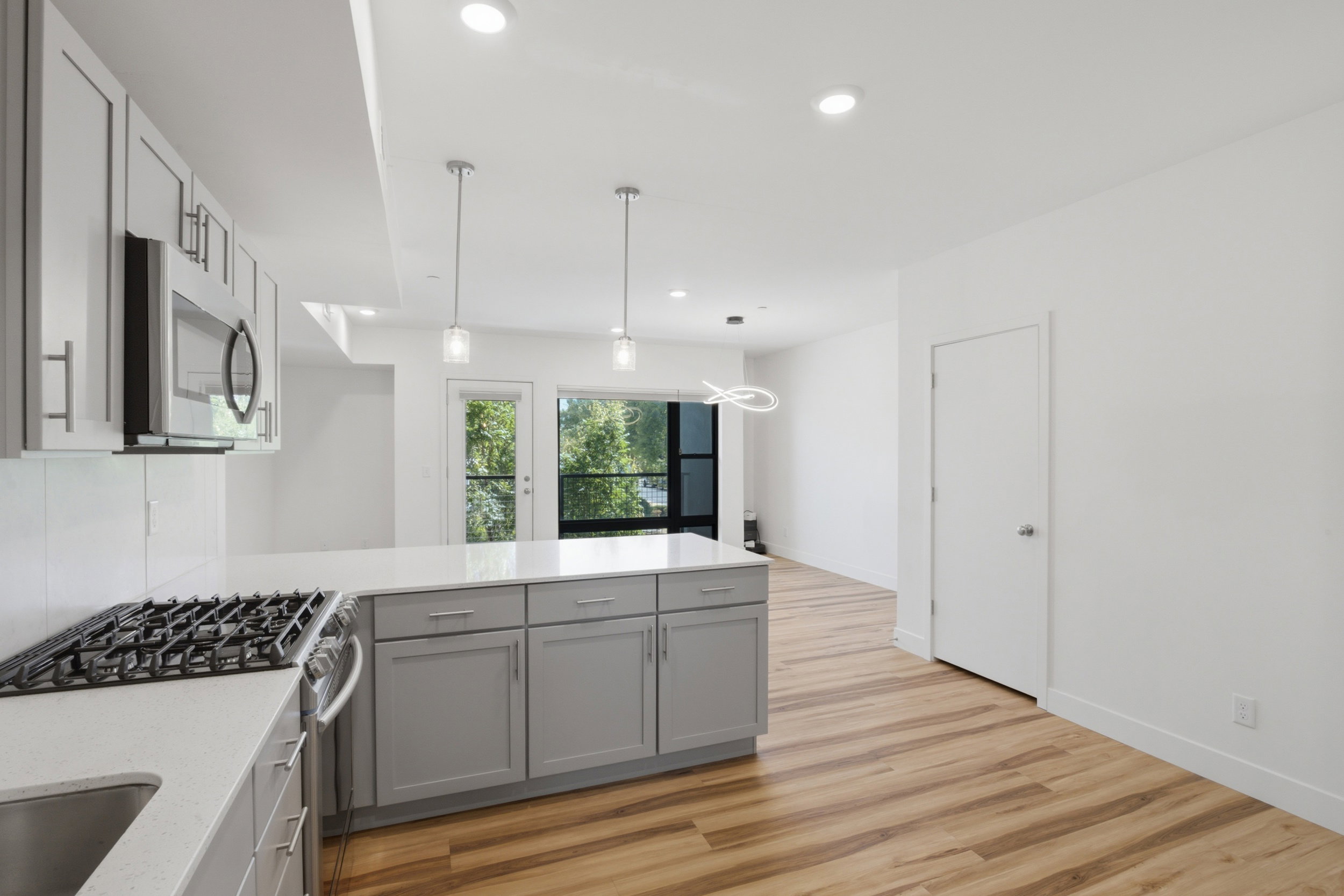 Modern kitchen featuring stainless steel appliances, light gray cabinetry, quartz countertops, and a gas range