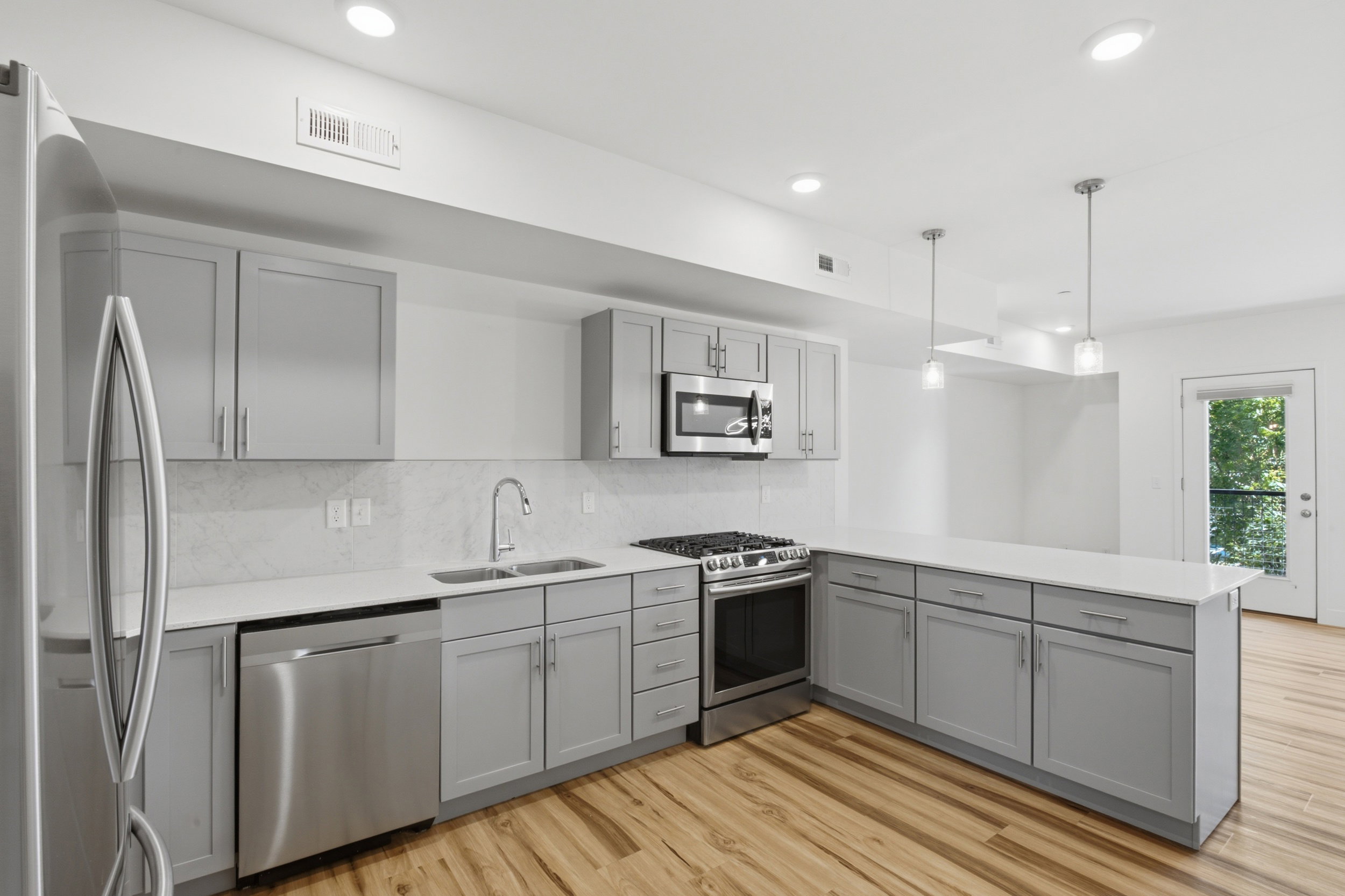 Modern kitchen featuring stainless steel appliances, light gray cabinetry, quartz countertops, and a gas range