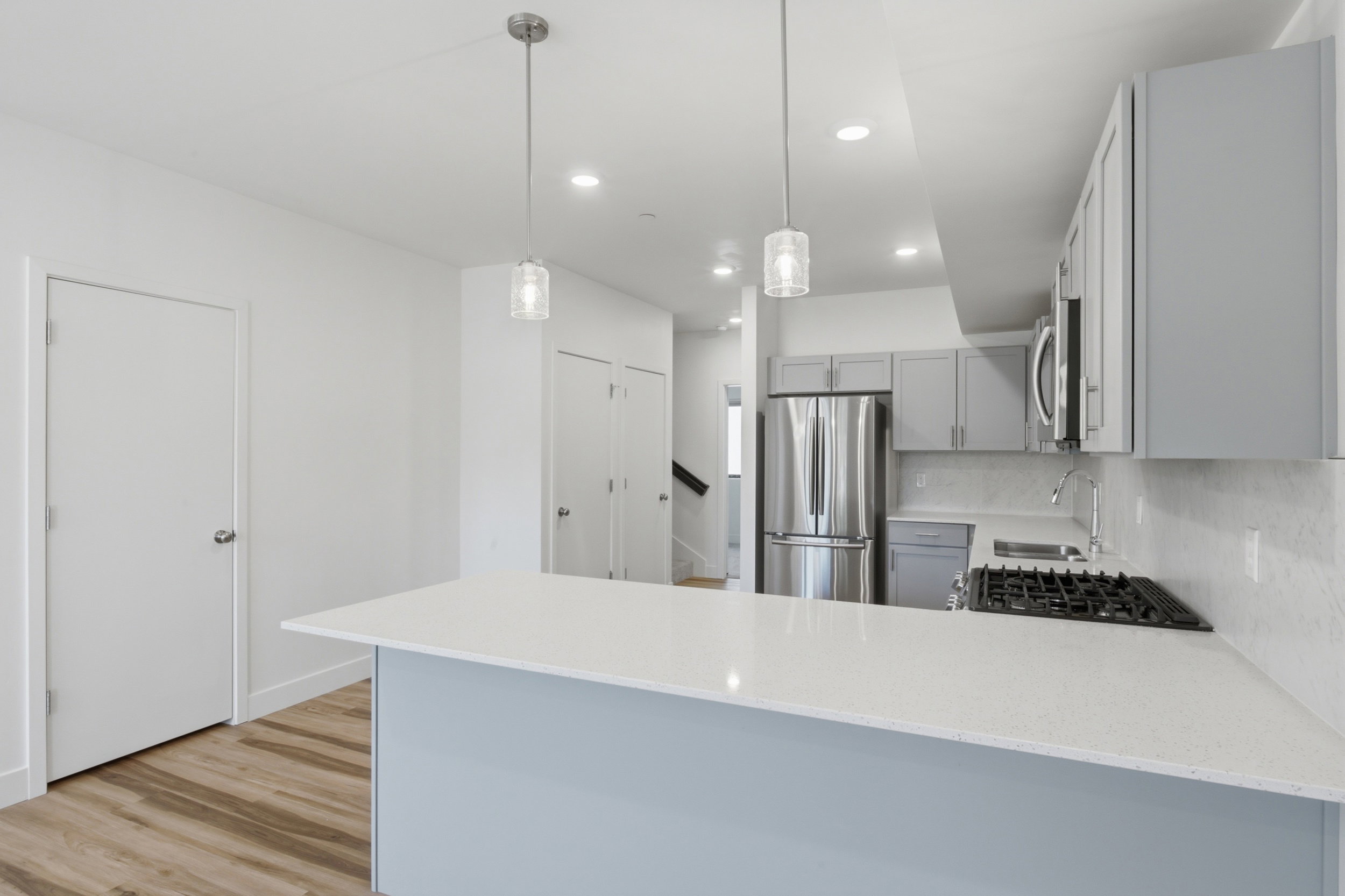Kitchen bar seating with a white quartz countertop and two pendant lights