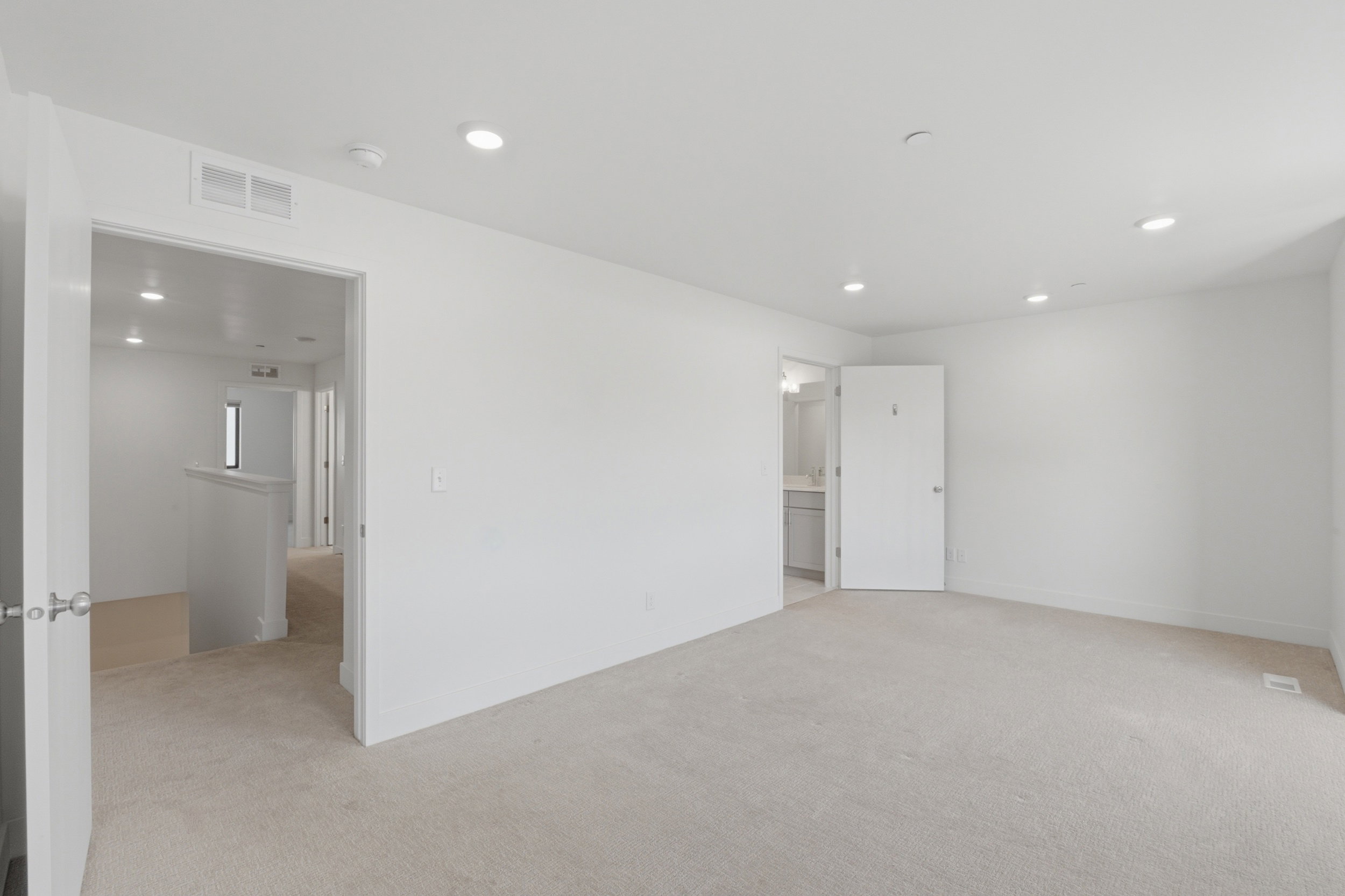 Spacious primary bedroom featuring an ensuite bathroom and large walk in closet