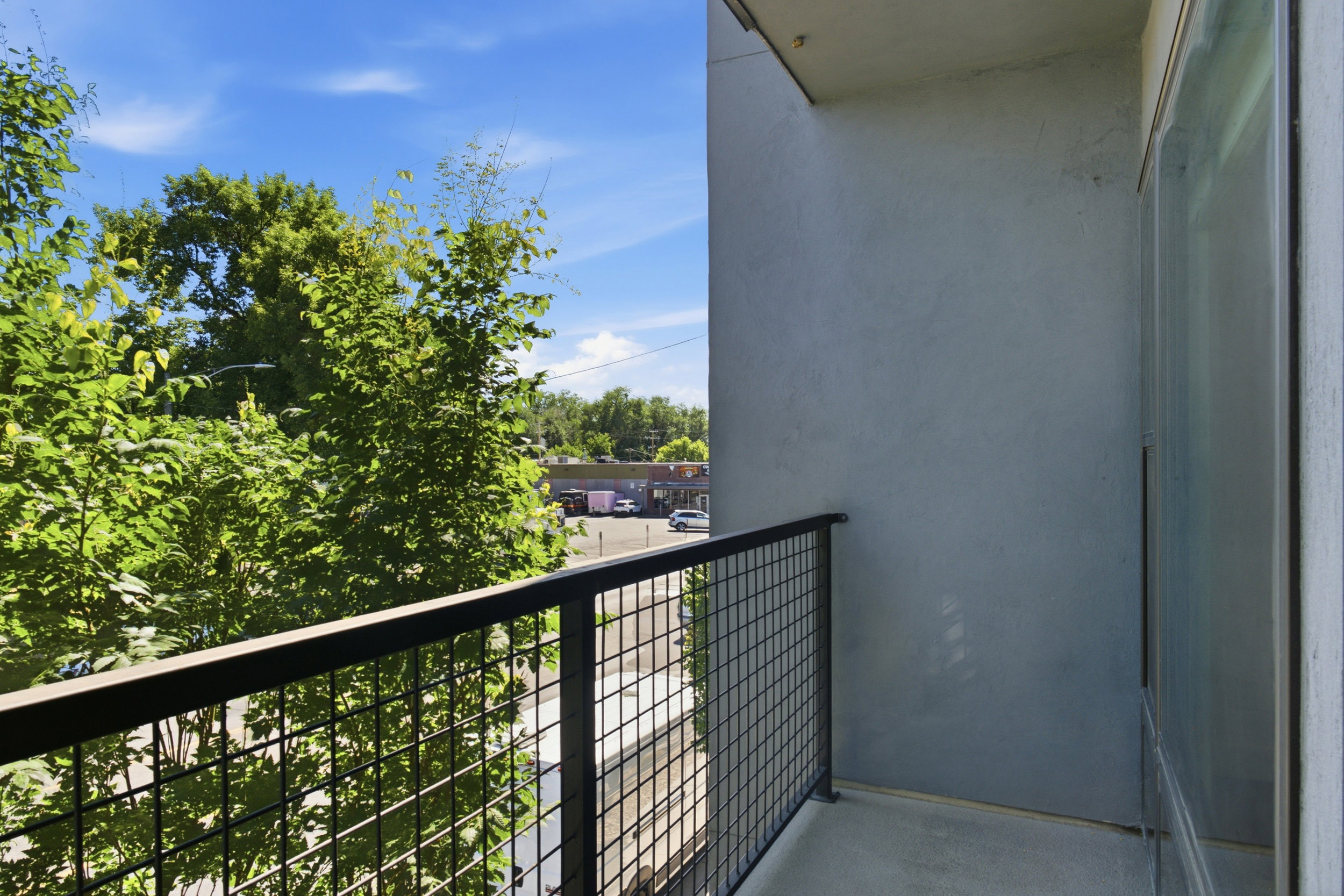 Private balcony with a metal grid railing and concrete flooring