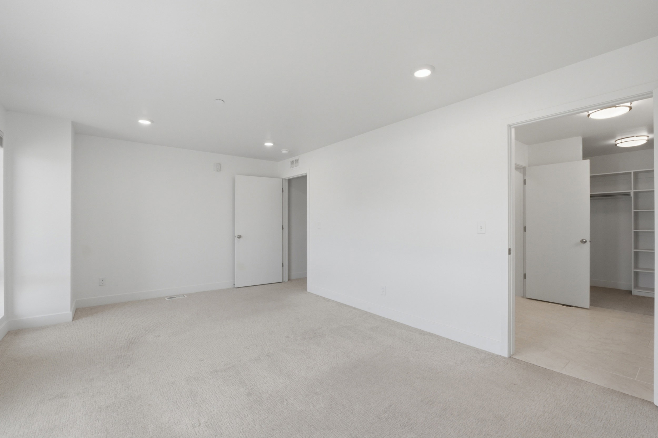 Spacious primary bedroom featuring an ensuite bathroom and large walk in closet