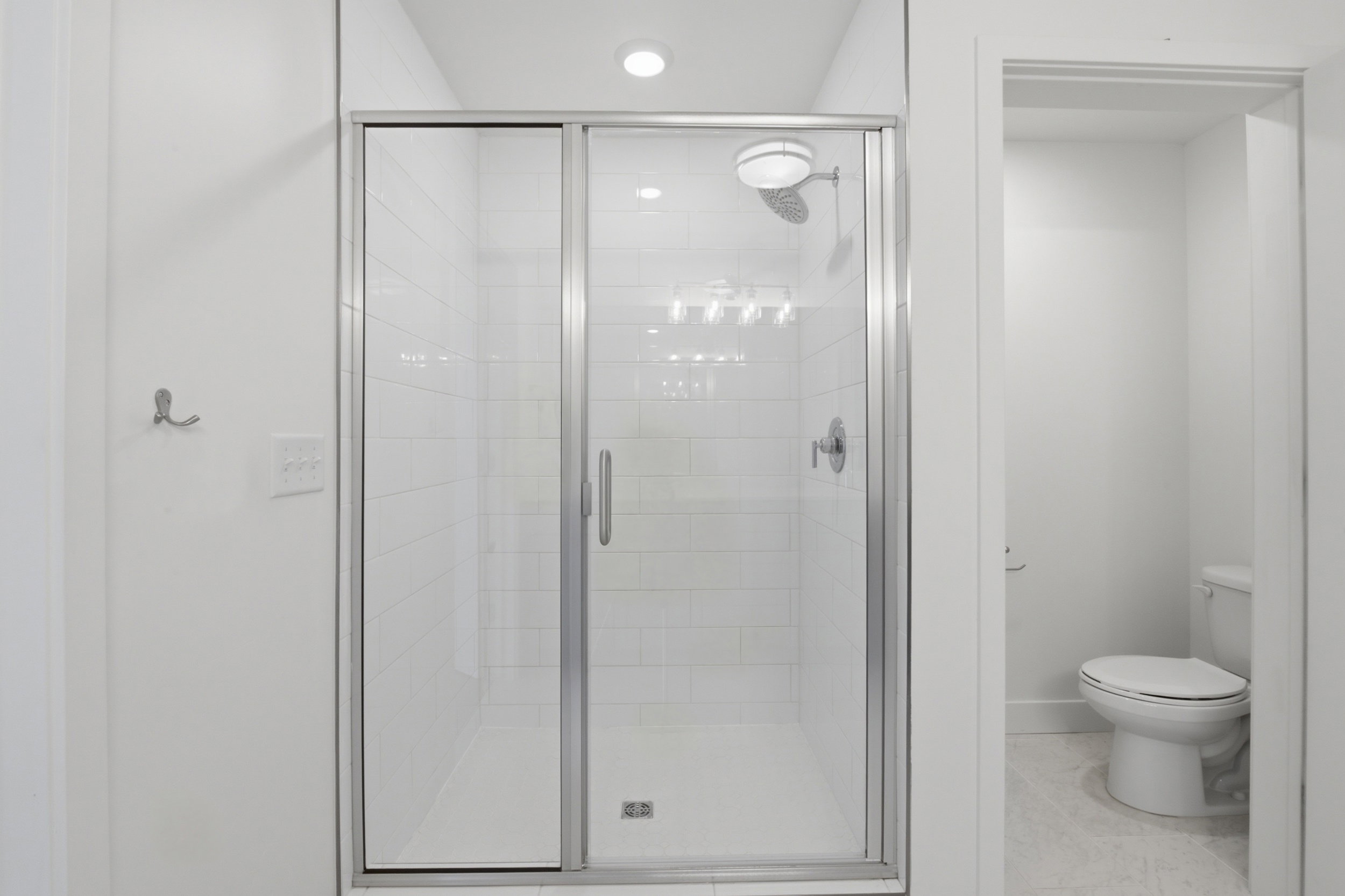 Glass-enclosed shower with subway tile surround in primary bathroom