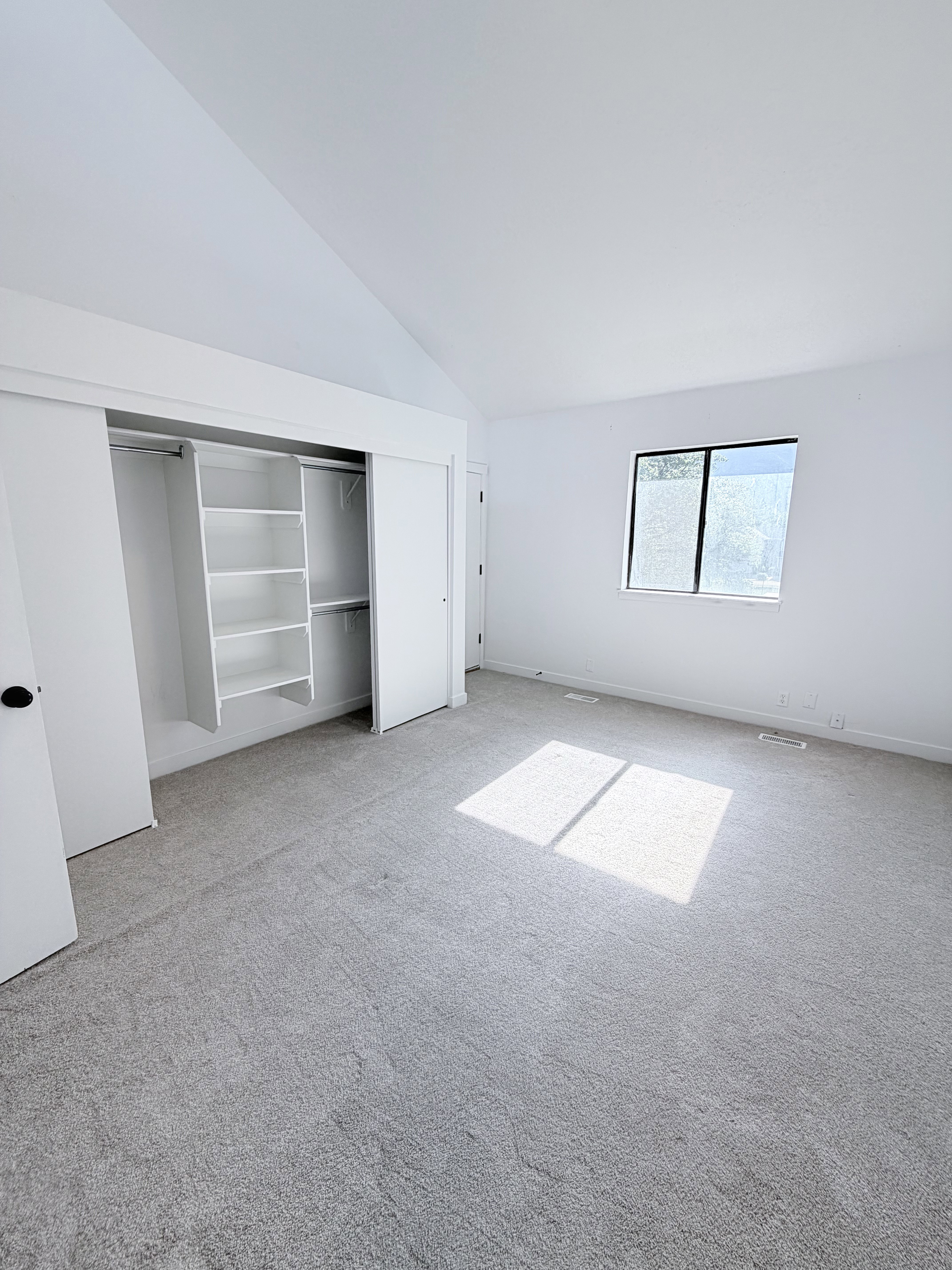 Interior room featuring a vaulted ceiling and light gray carpeting