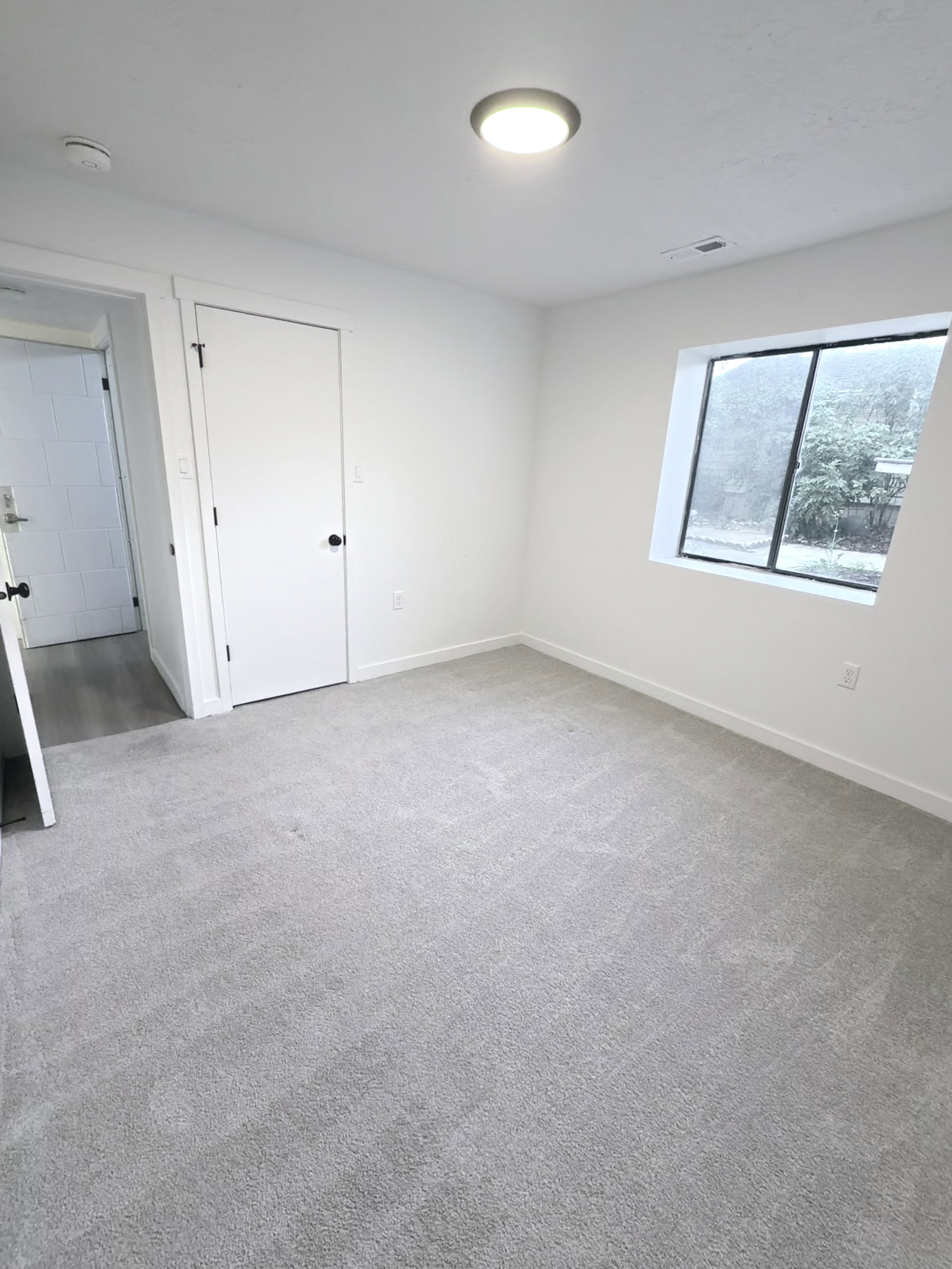 Bright interior space featuring light gray carpeting and white walls