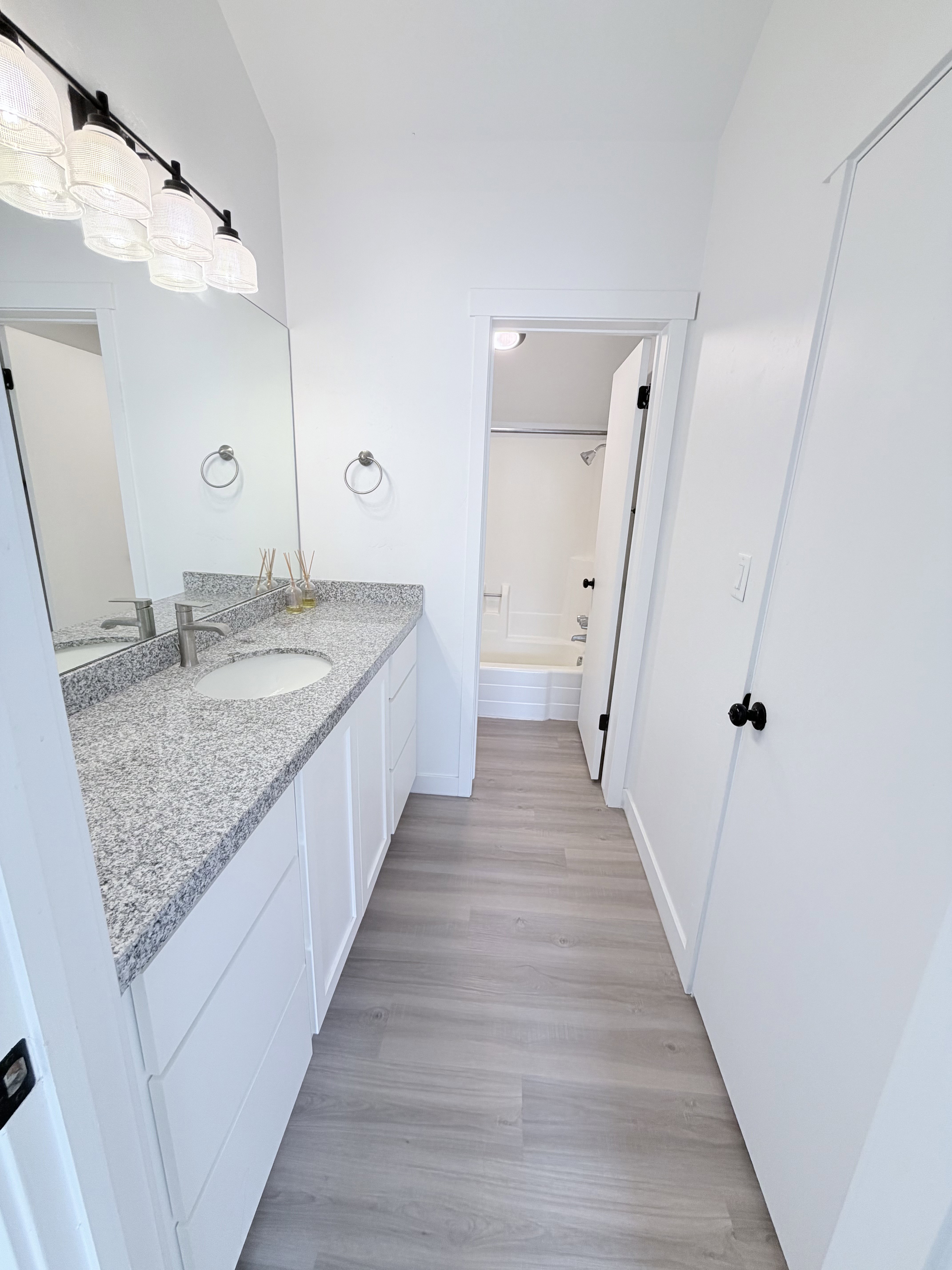 Bathroom featuring an extended vanity with a light-colored speckled countertop, undermount sink, and modern black hardware