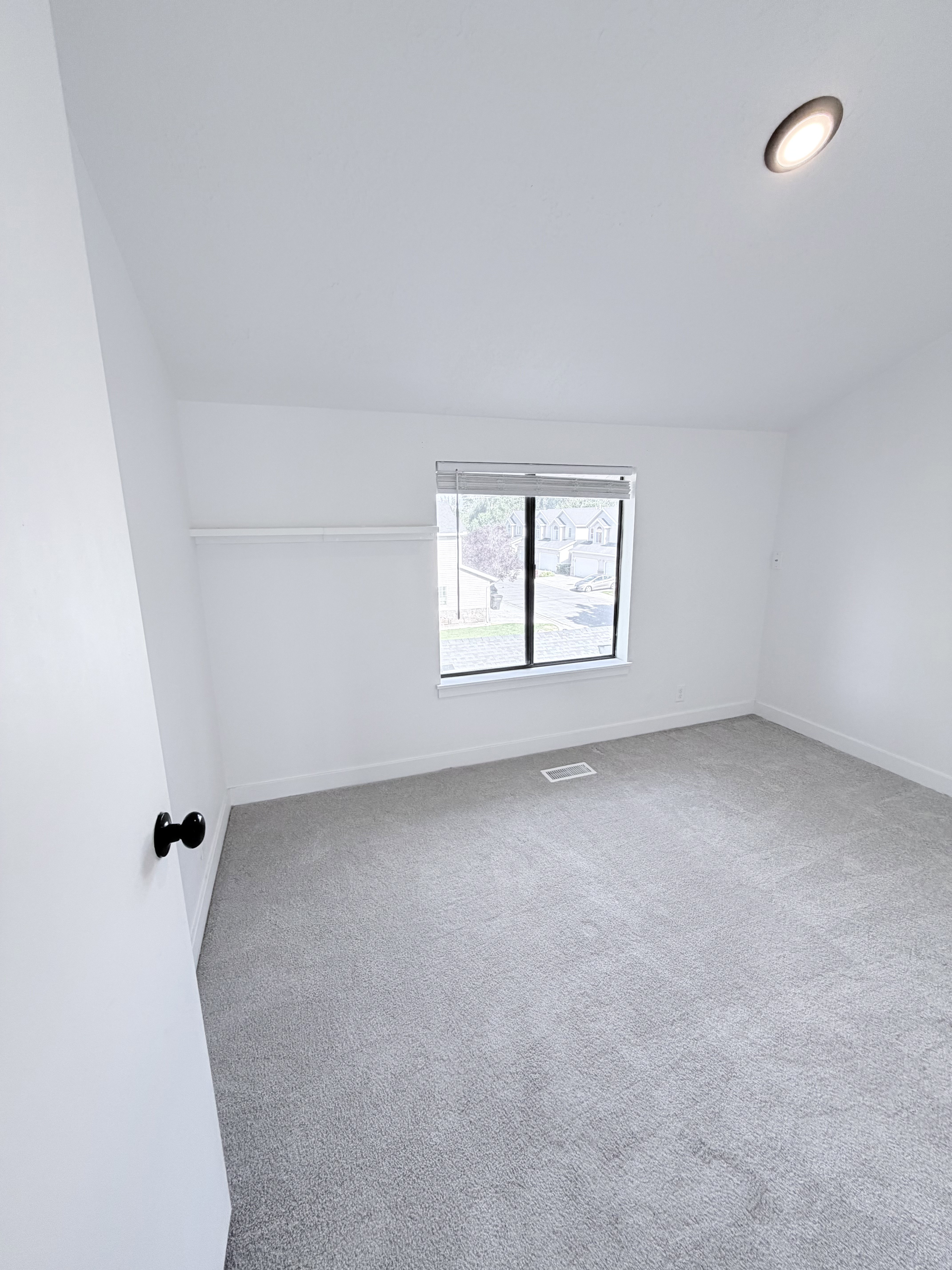 Carpeted interior space featuring a window with blinds, recessed ceiling lighting, and a closet with a shelf and hanging rod