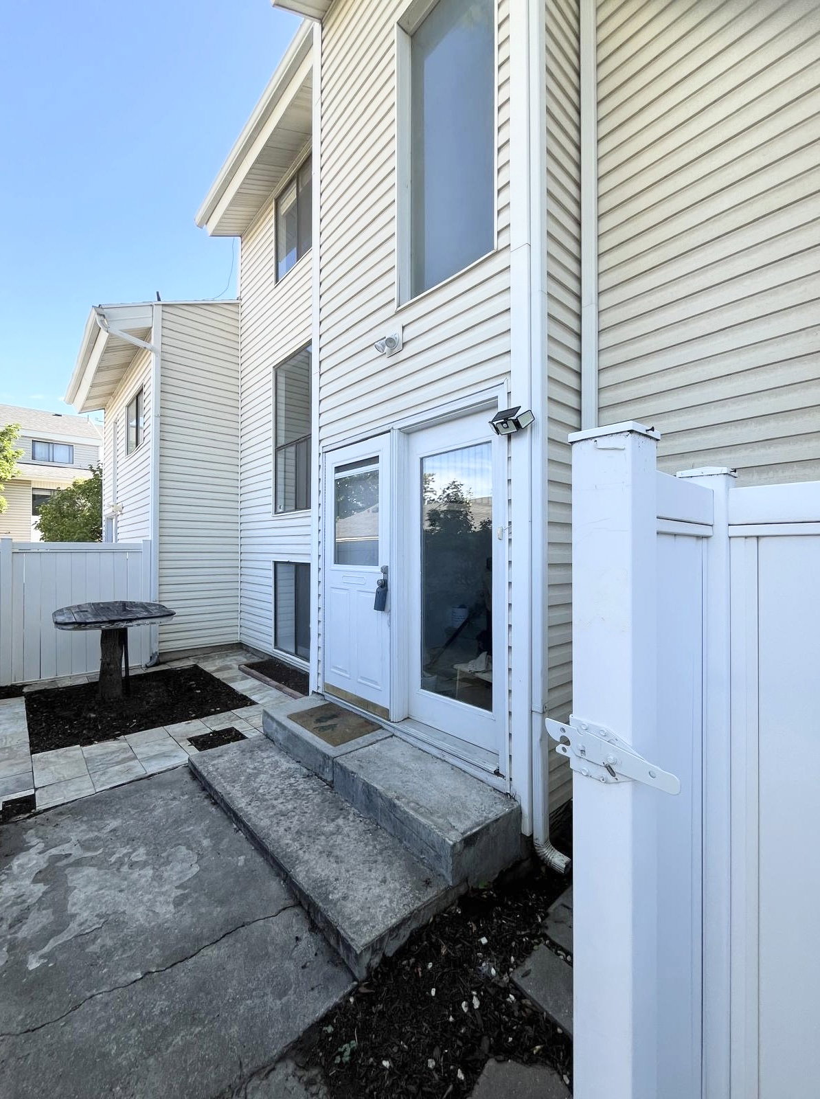 White vinyl siding exterior with an upper-level large picture window and a ground-level glass-paneled entry door