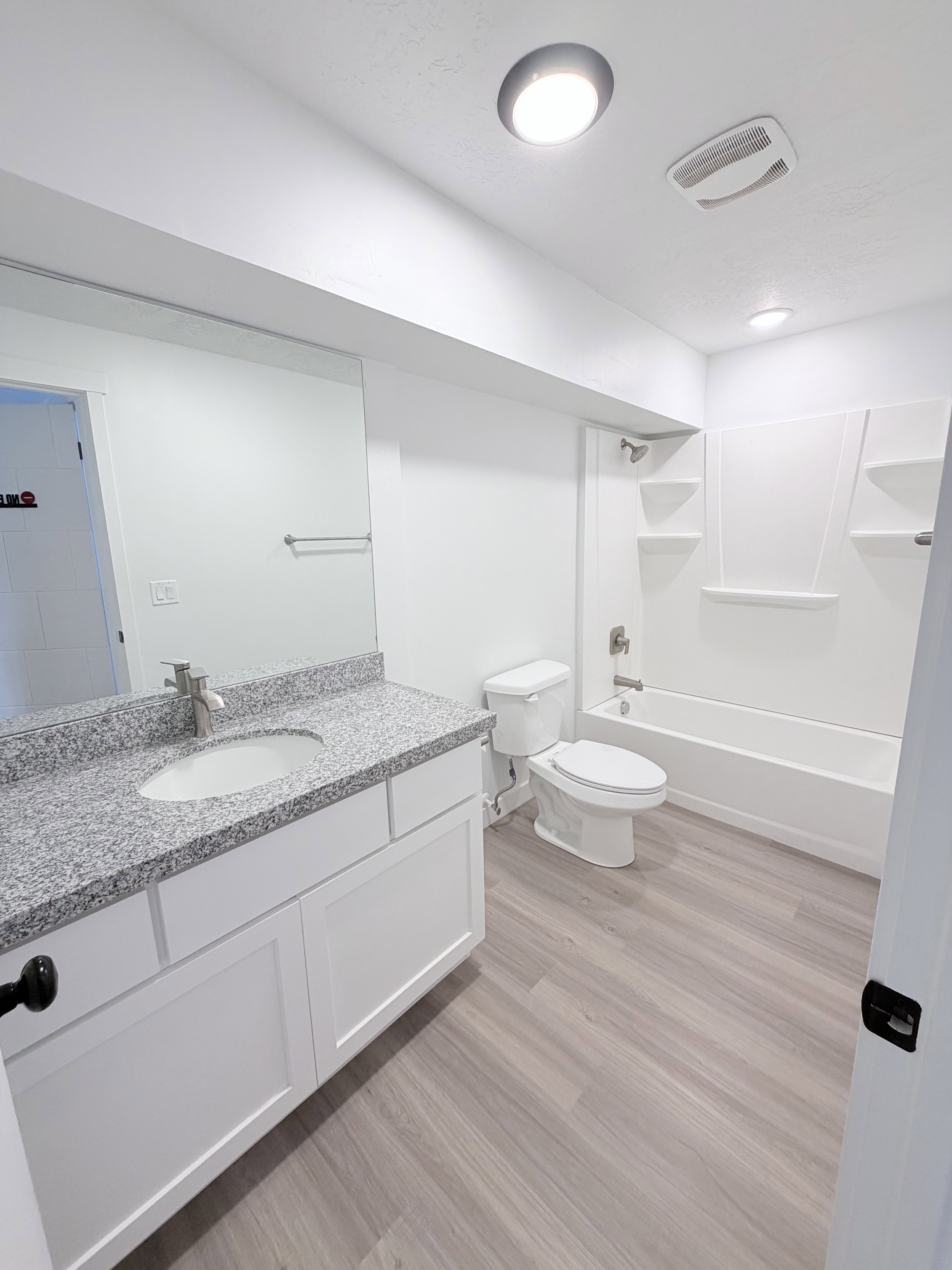 Contemporary bathroom featuring a white vanity with a speckled countertop, a undermount sink, and a chrome faucet