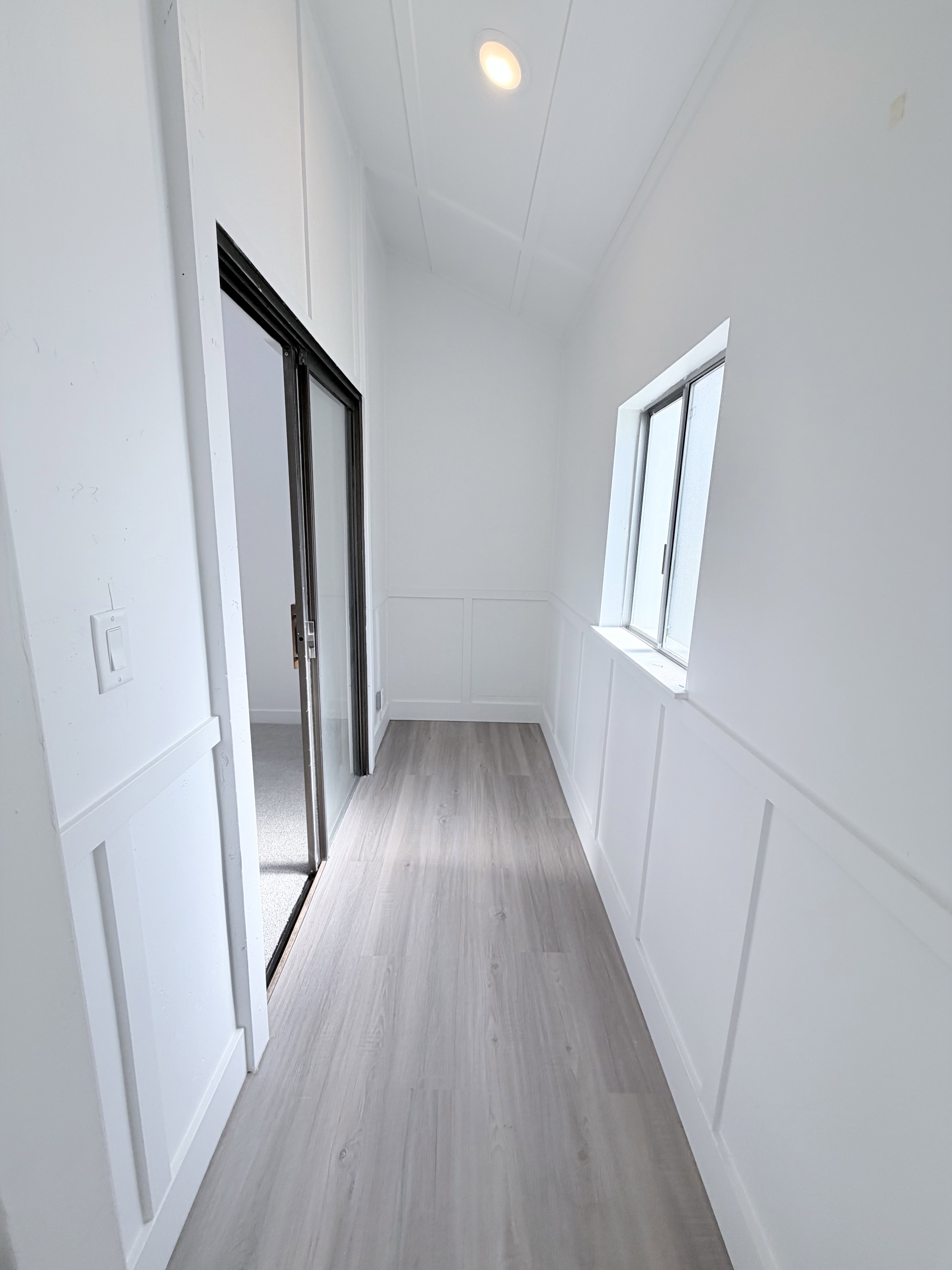 Hallway featuring wainscoting, wood-finish flooring, recessed lighting, and a sliding glass door