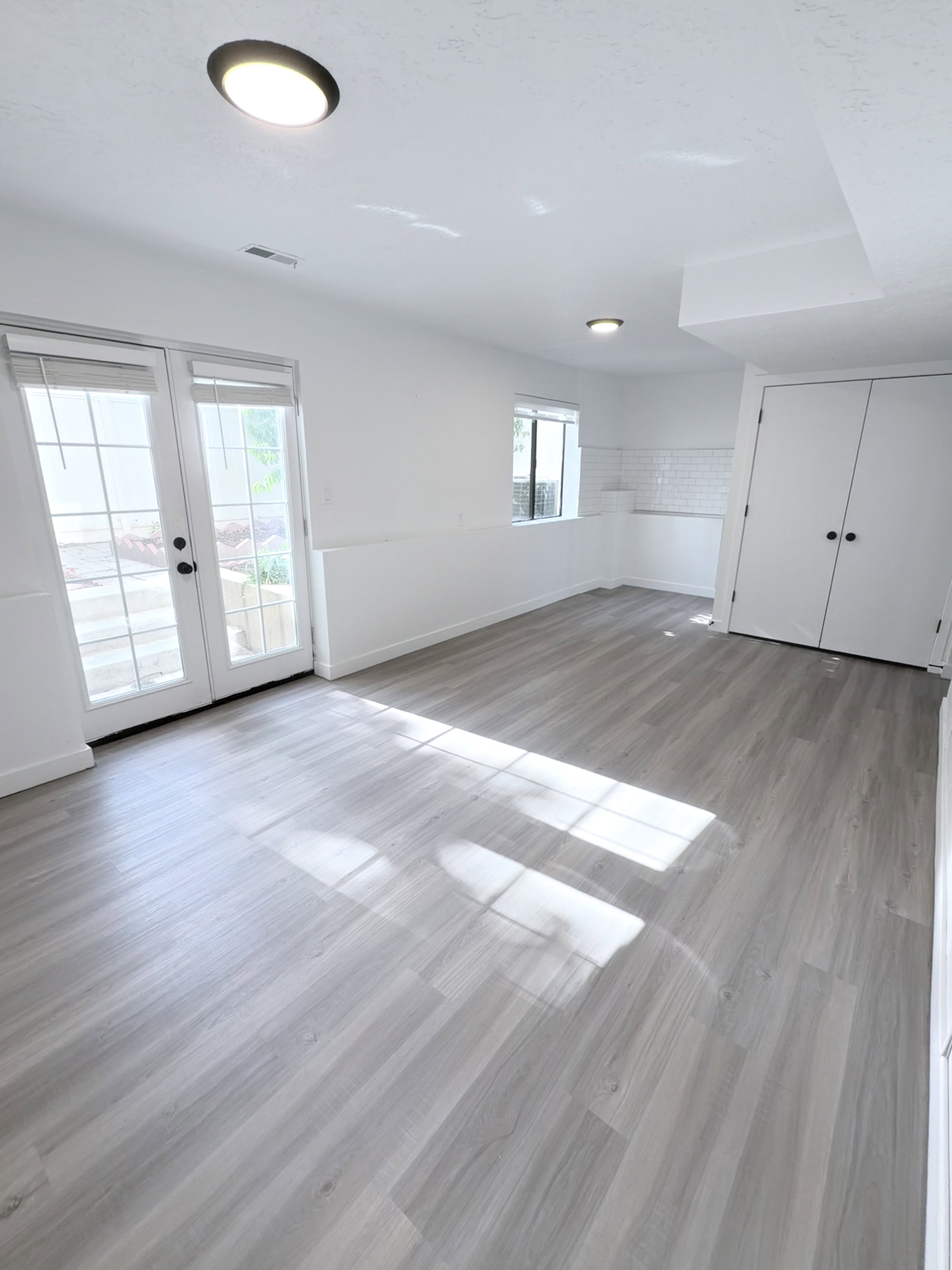 Spacious room featuring light wood-finish flooring, recessed lighting, and white walls