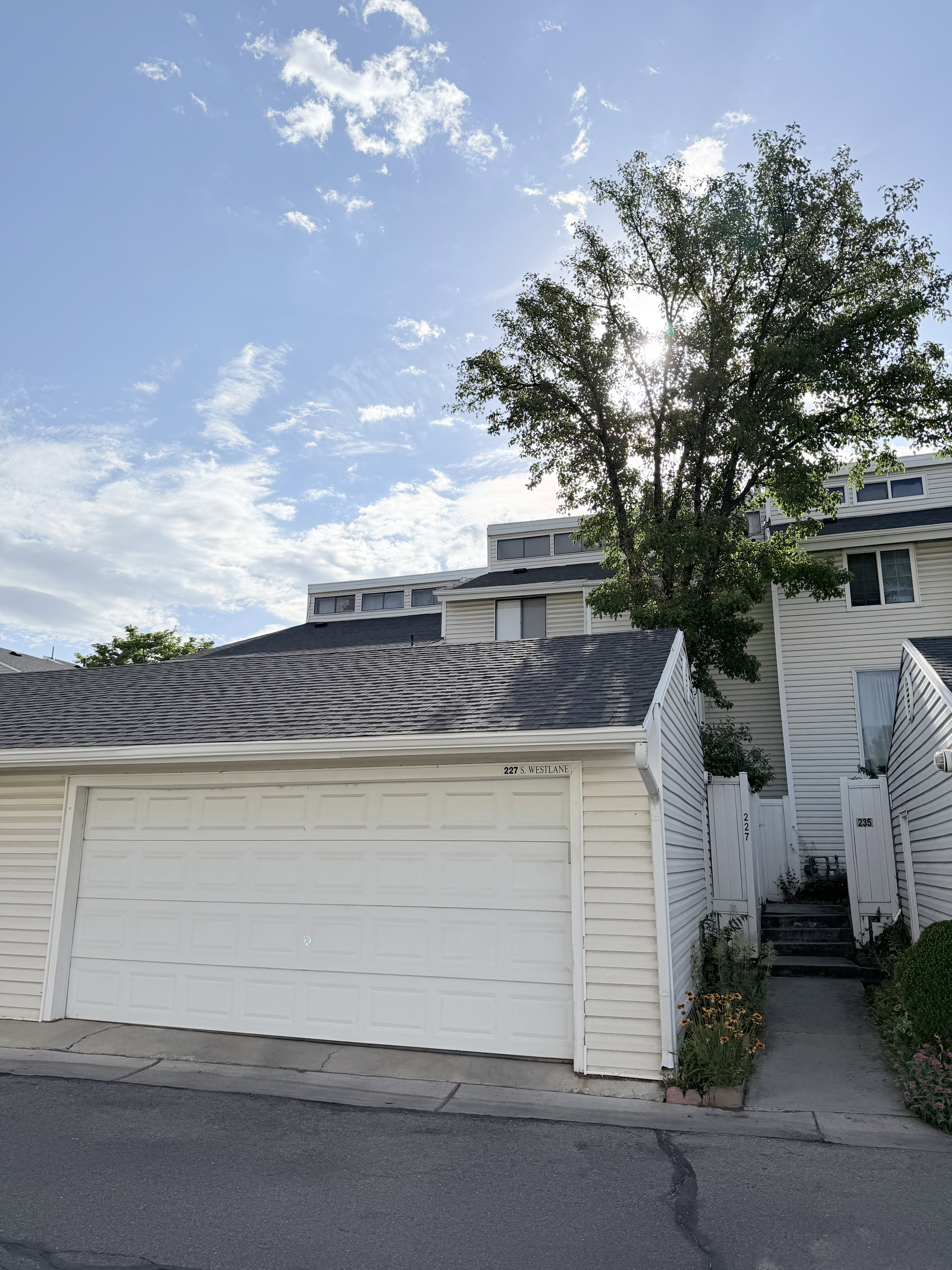Double-car garage with a paneled white door, asphalt driveway, and light-colored siding