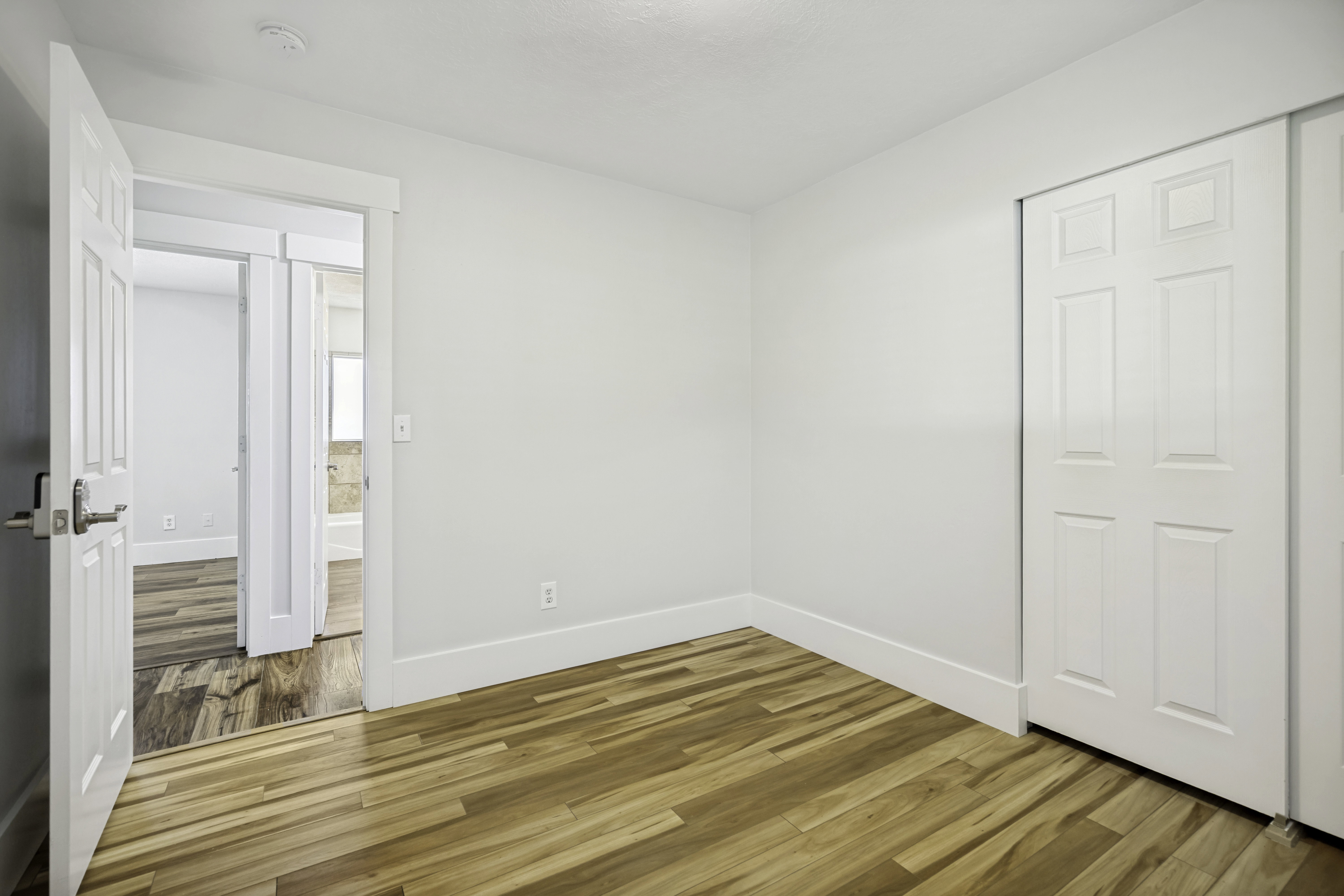 Room featuring wood-finish flooring, white walls, and white baseboards