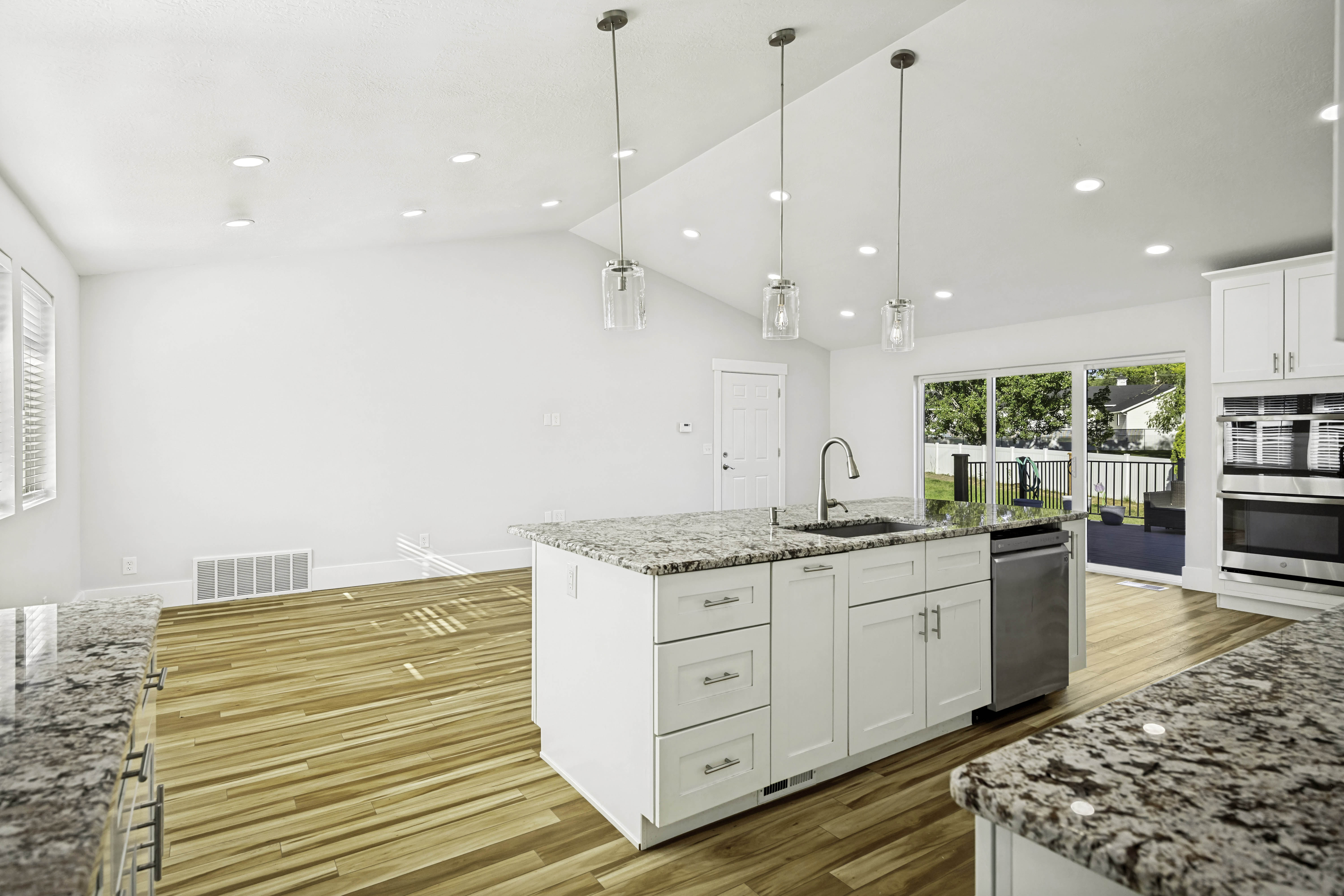 Kitchen featuring an expansive island with granite countertops, stainless steel appliances, and white cabinetry