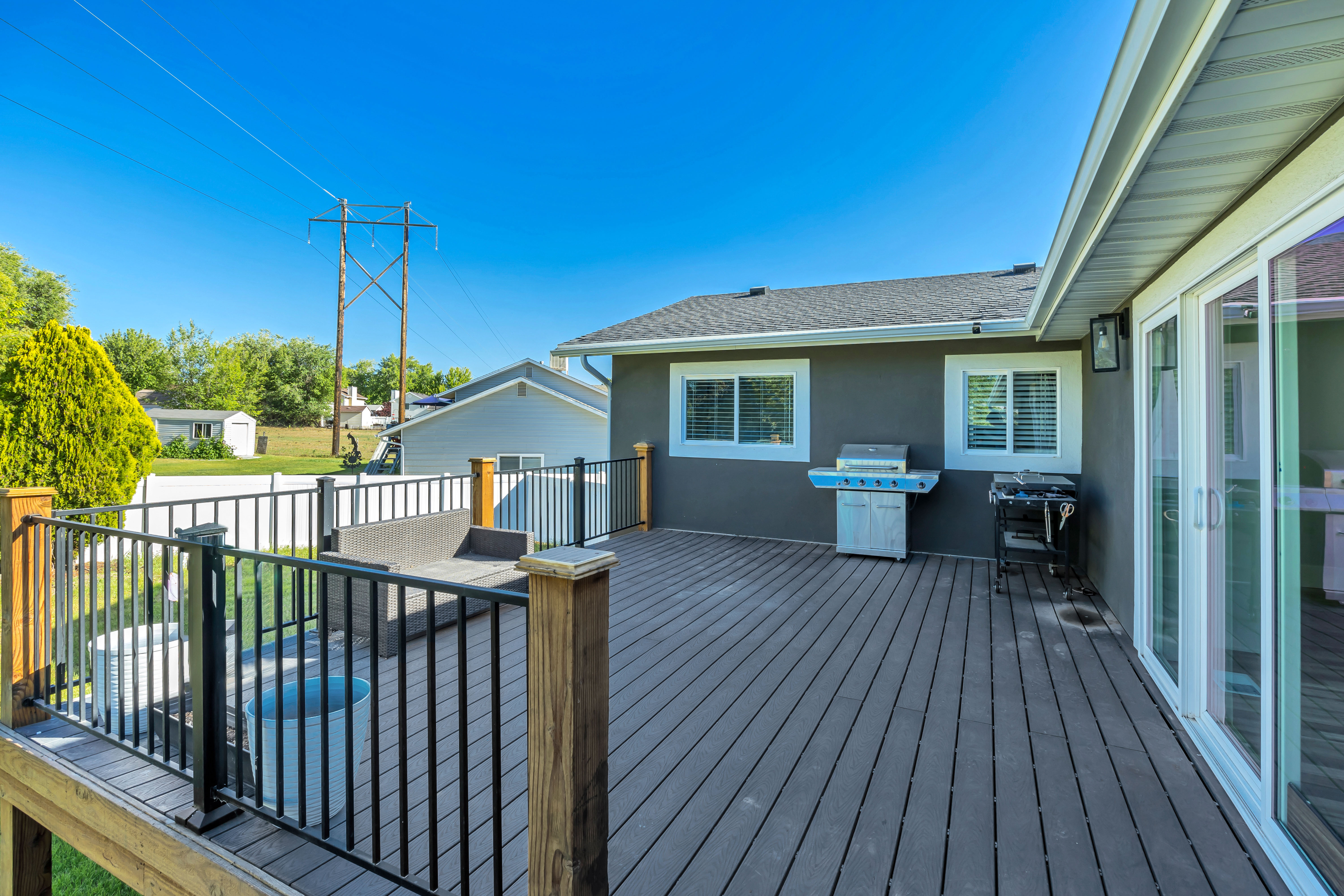 Spacious composite deck with dark railings and natural wood posts, featuring a built-in spa