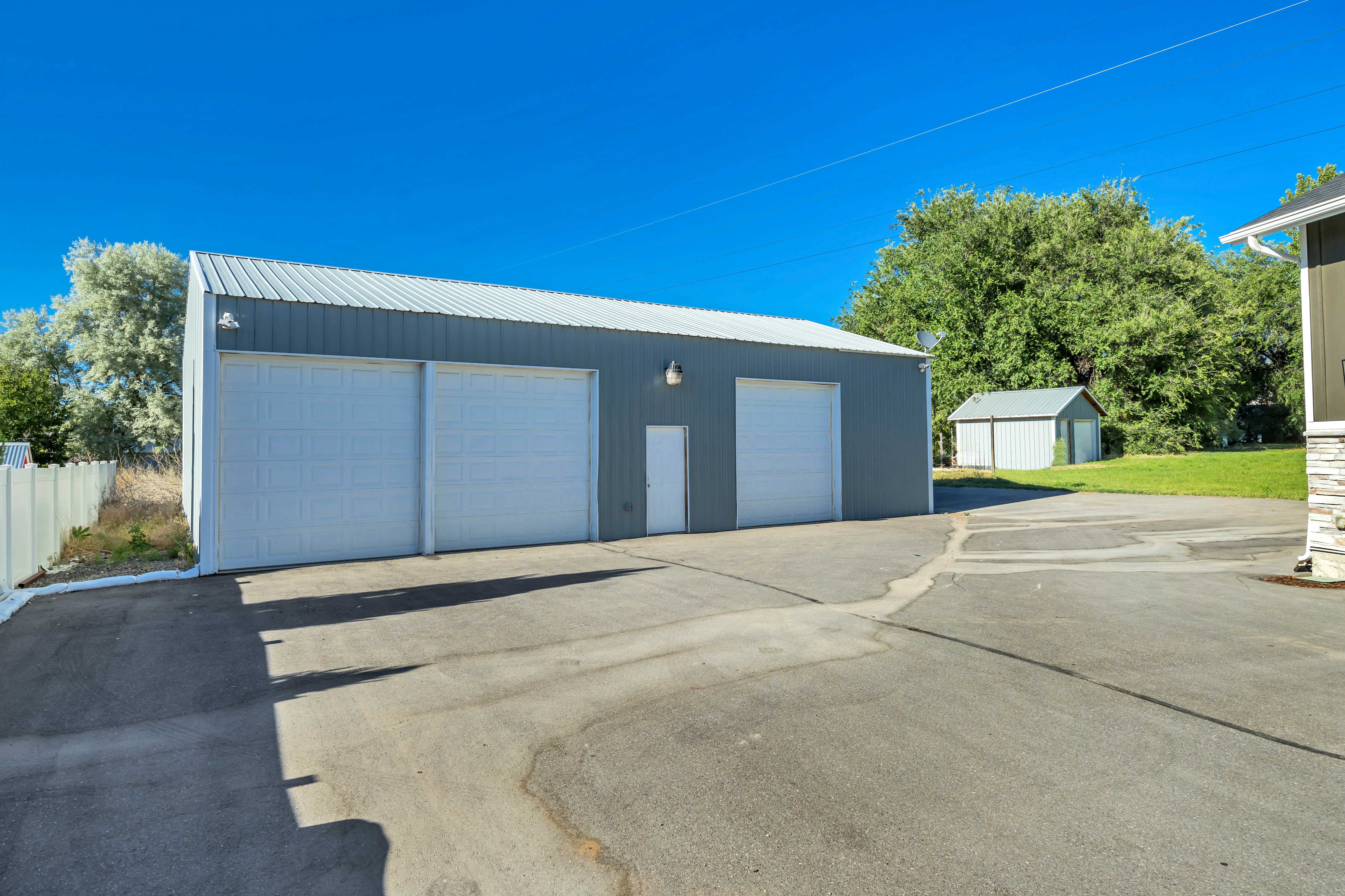 Spacious metal outbuilding featuring three garage doors and a separate entry door, with a corrugated metal roof