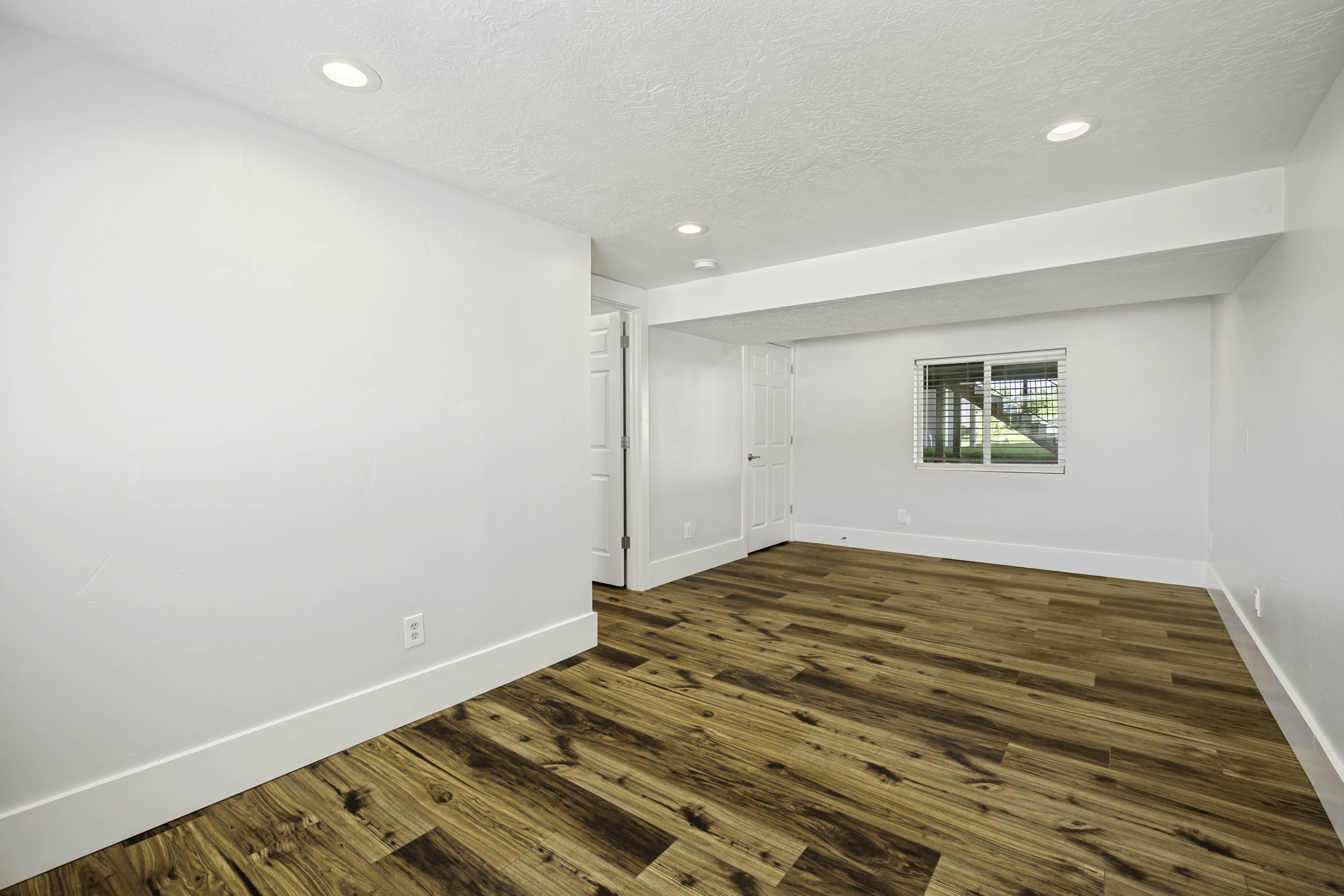 Spacious room featuring wood-finish flooring, recessed lighting, and white walls