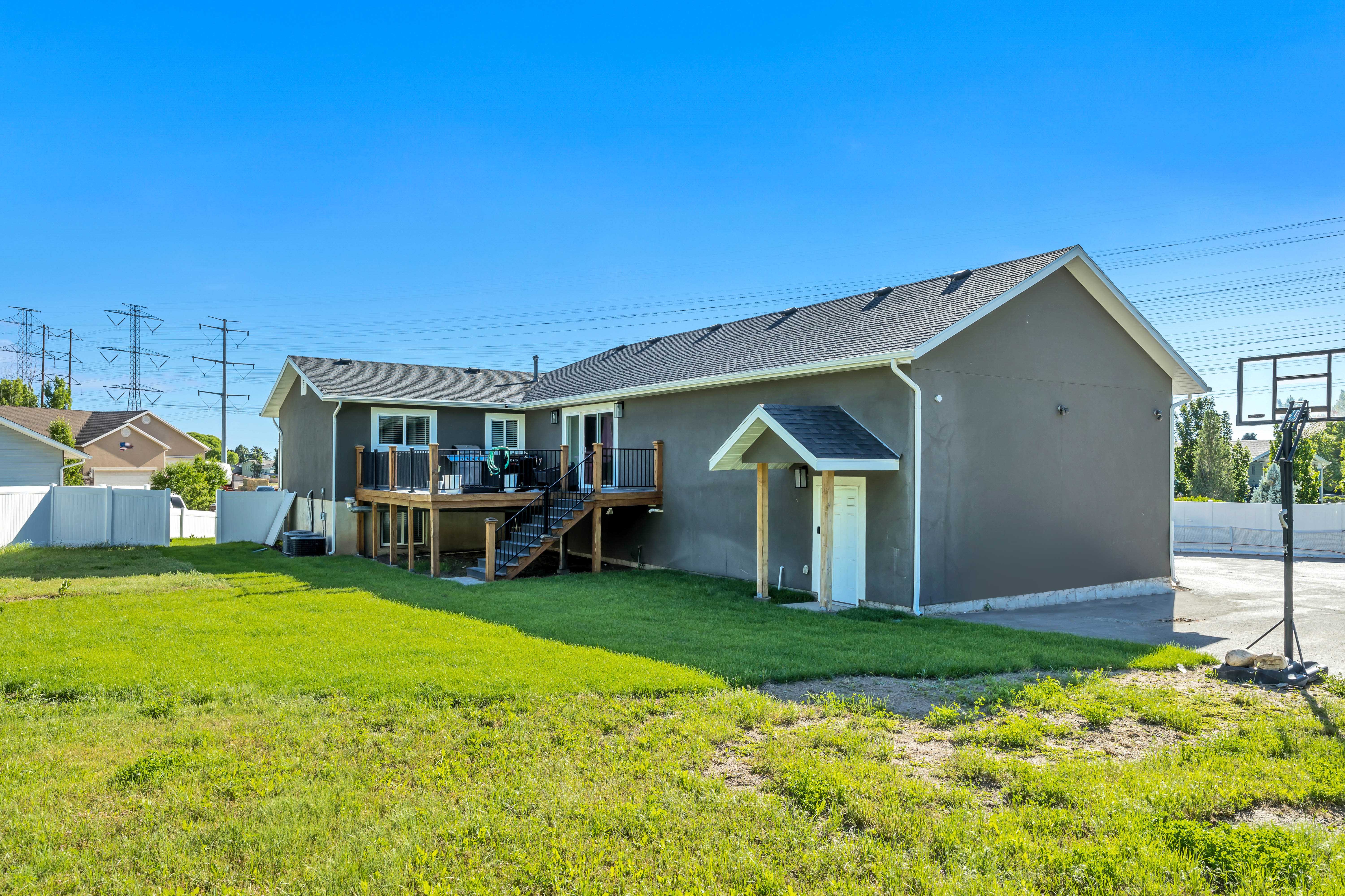 Expansive rear exterior featuring a substantial wooden deck with dark railings and steps