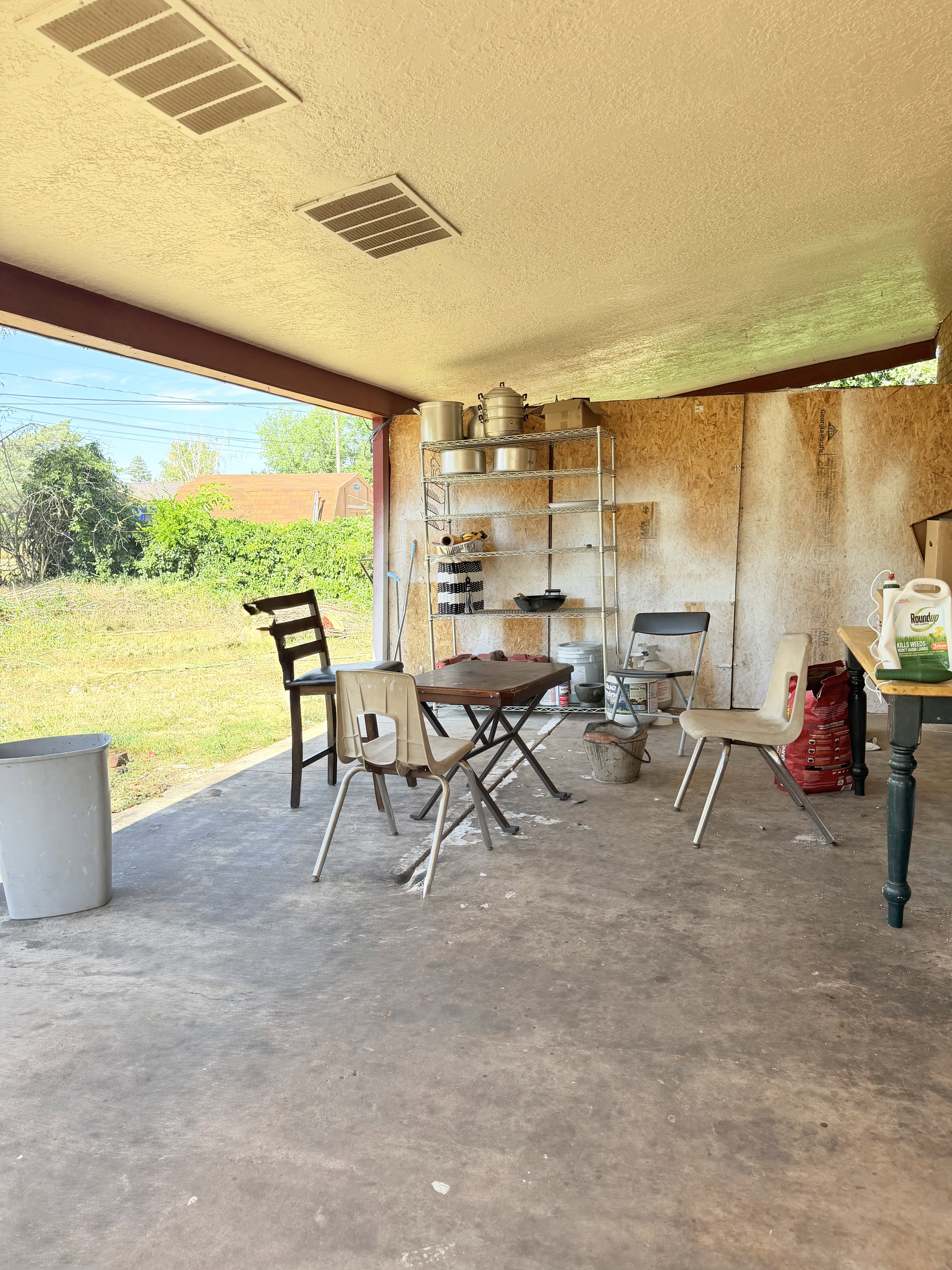 Covered patio space featuring a concrete floor, exposed structural beams, and a textured ceiling with two recessed vents