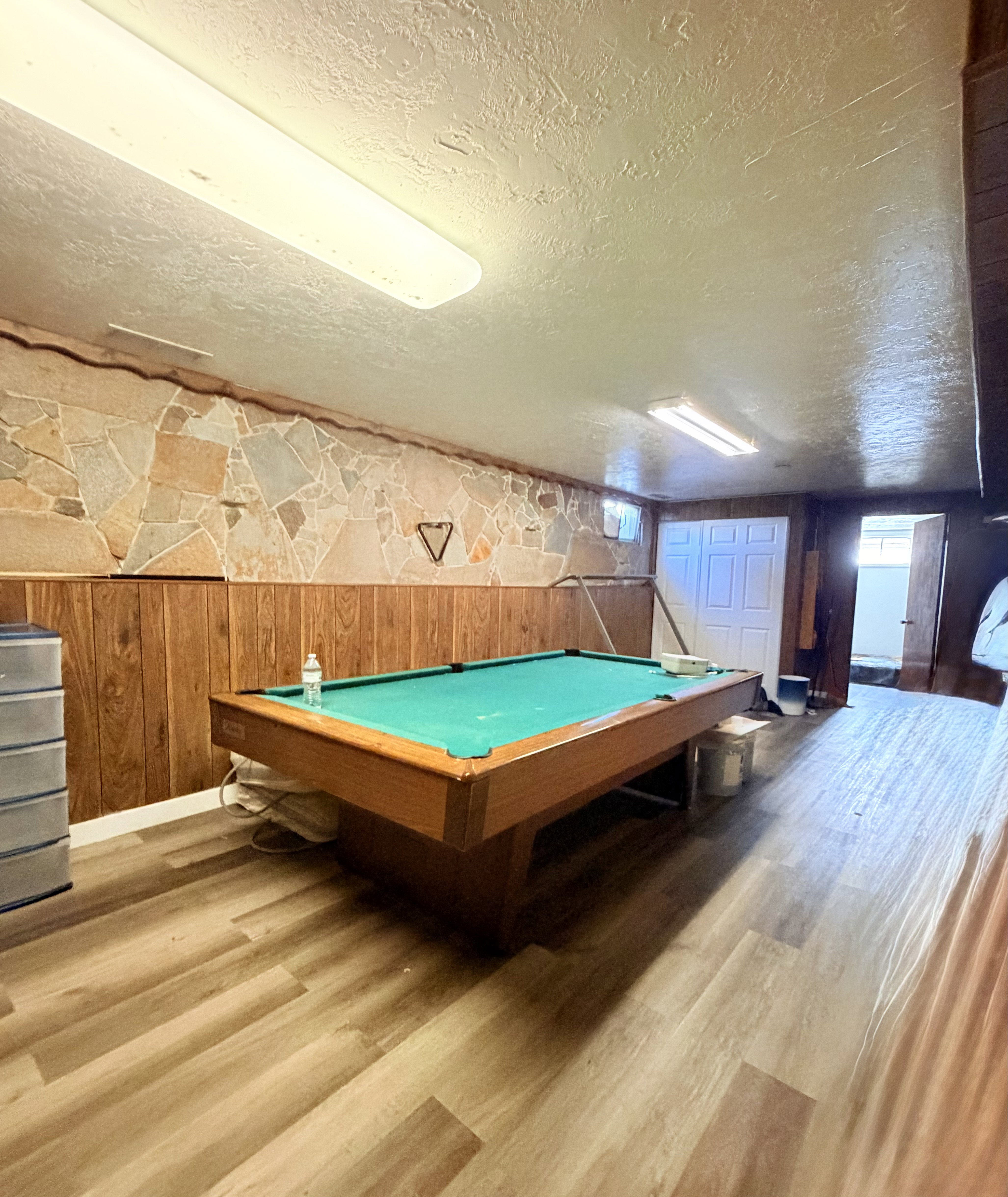 Recreation space featuring wood-finish flooring, stone accent wall, and wood paneling