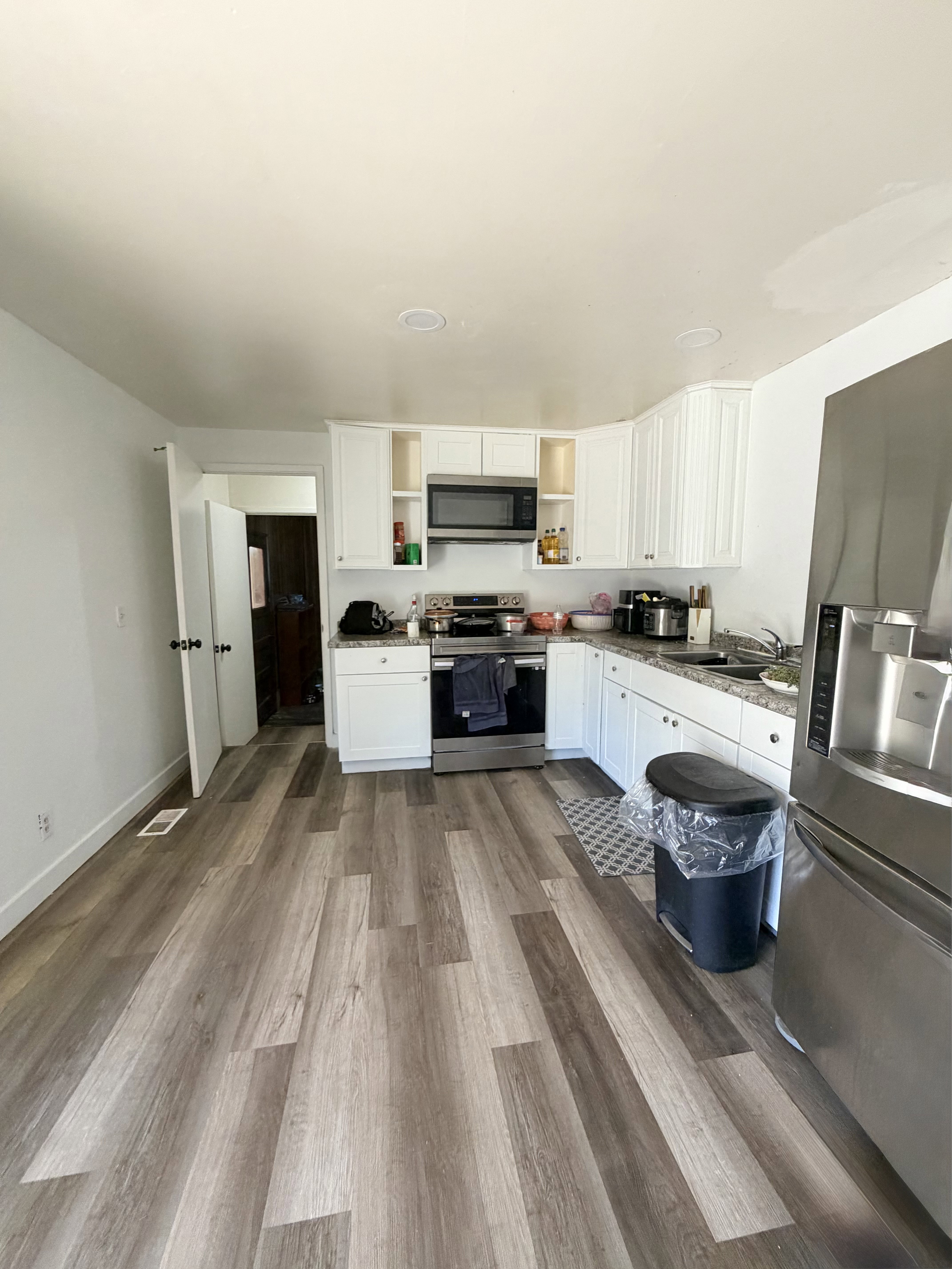 Kitchen featuring wood-finish plank flooring, white cabinetry, stainless steel appliances, speckled countertops, and recessed lighting
