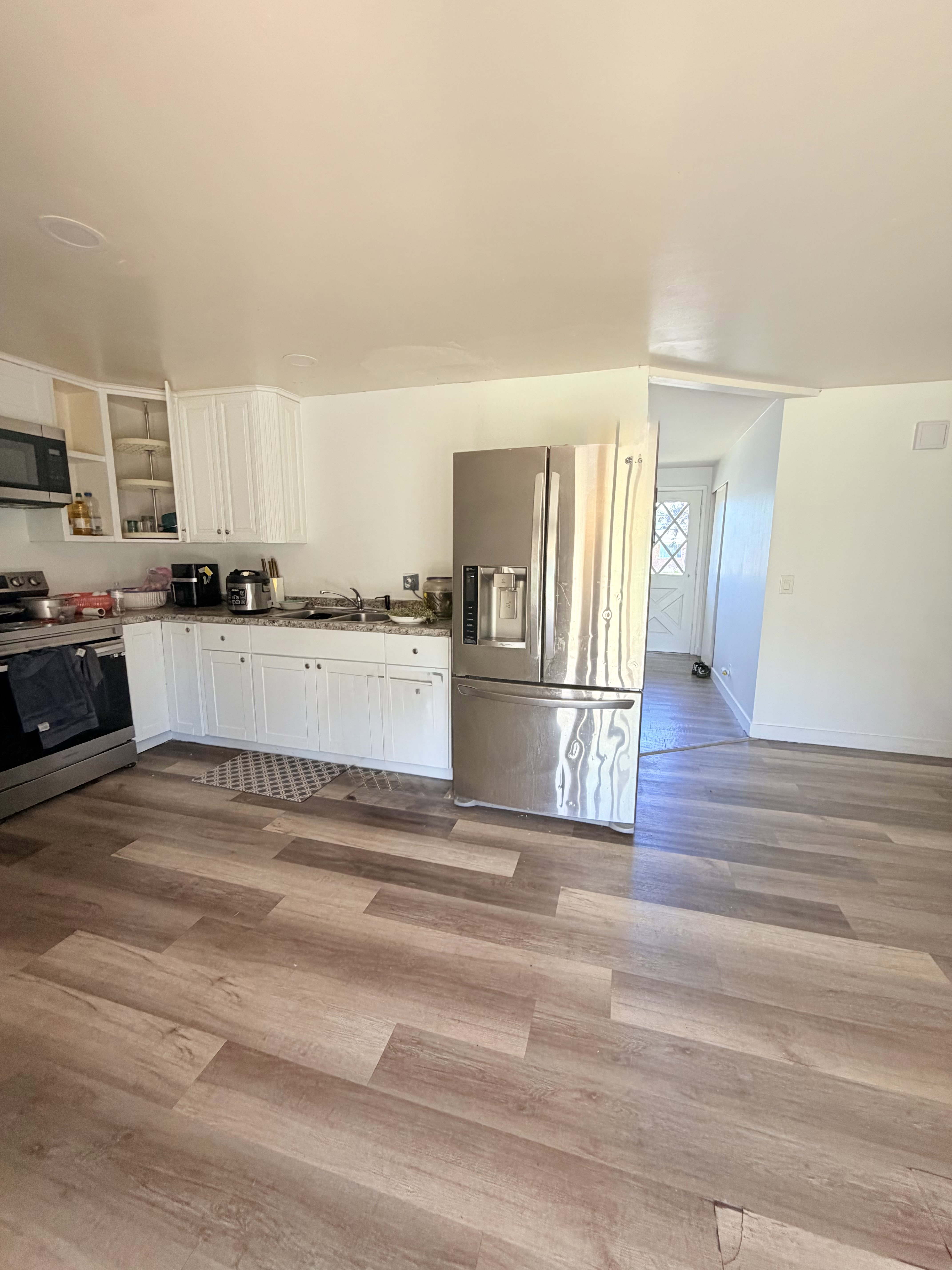 Kitchen featuring wood-finish flooring, white cabinetry, stainless steel appliances, and a built-in microwave