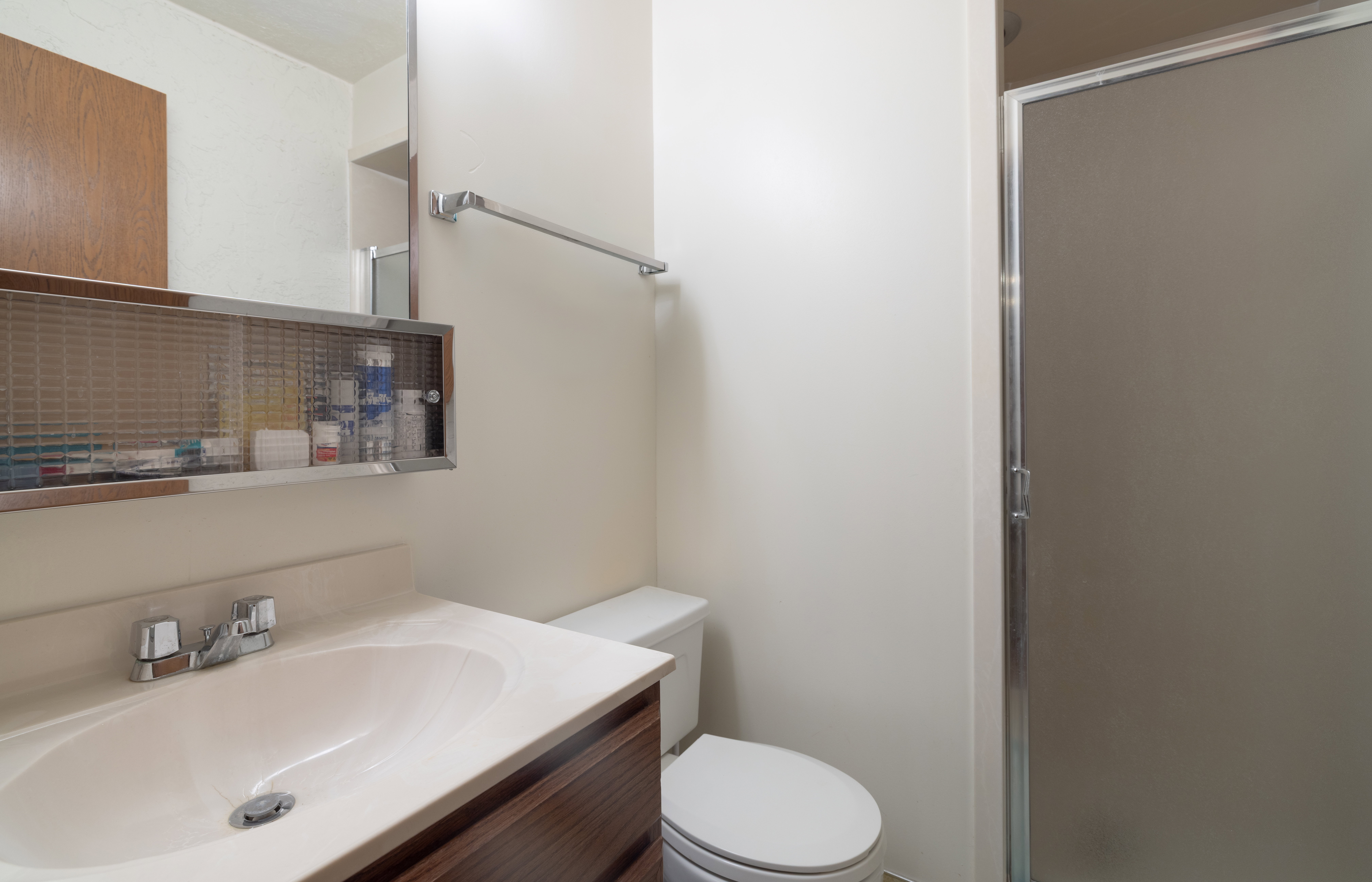 Bathroom featuring a vanity with an integrated sink, a wood-finish cabinet, and a mirrored medicine cabinet