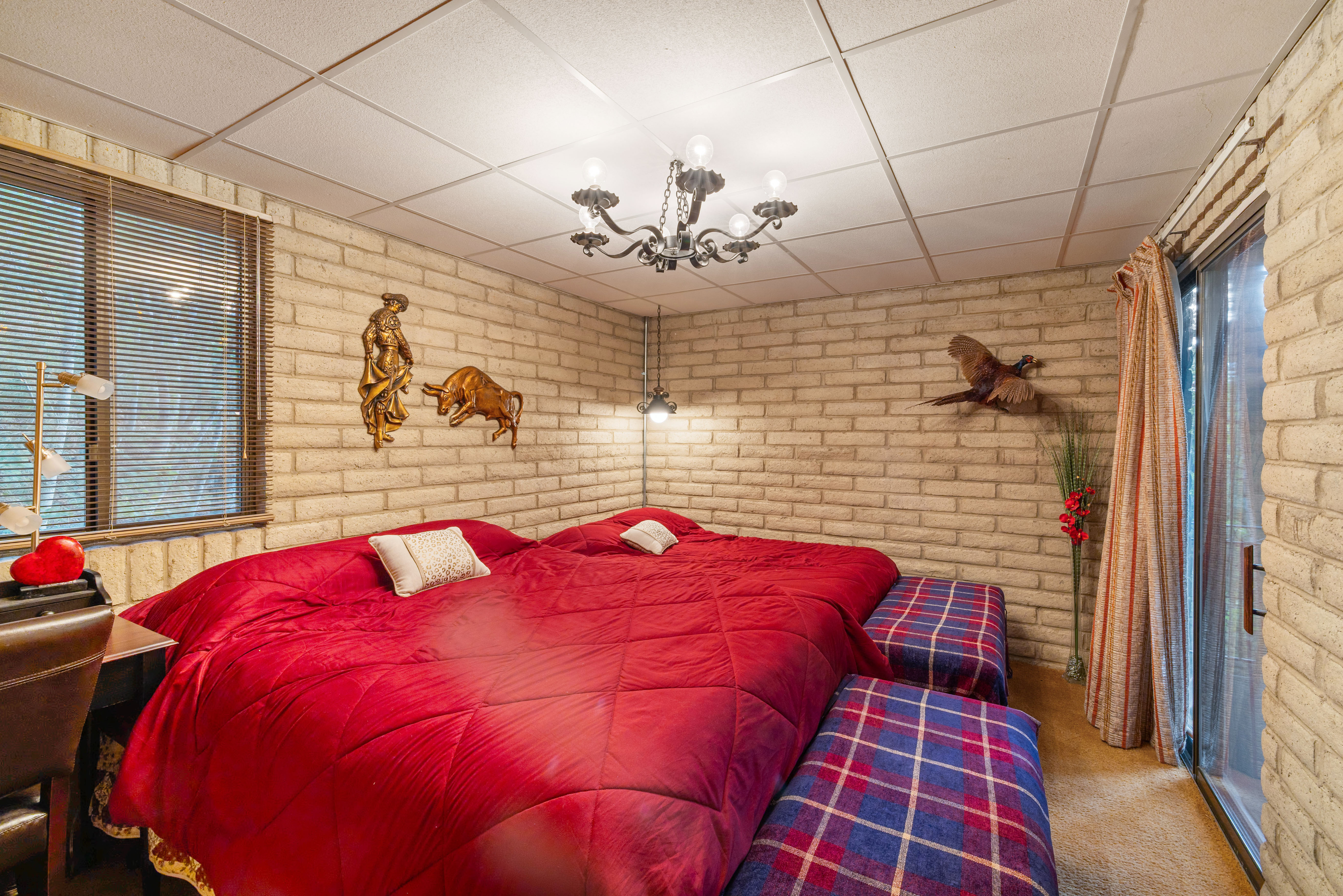 Bedroom featuring exposed brick walls, drop ceiling, and carpeted flooring