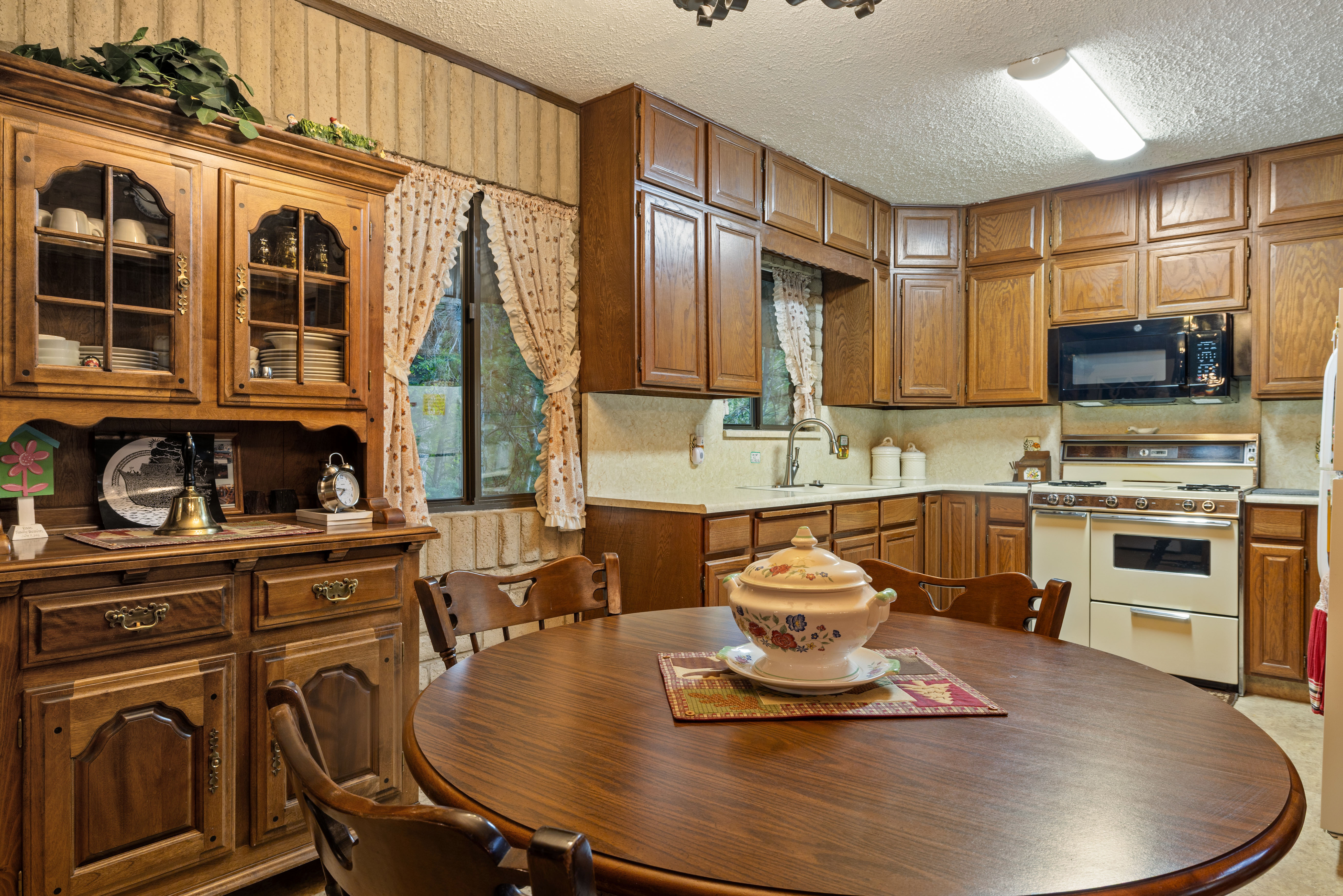 Kitchen featuring wood cabinetry, white countertops, a built-in microwave, and a classic range