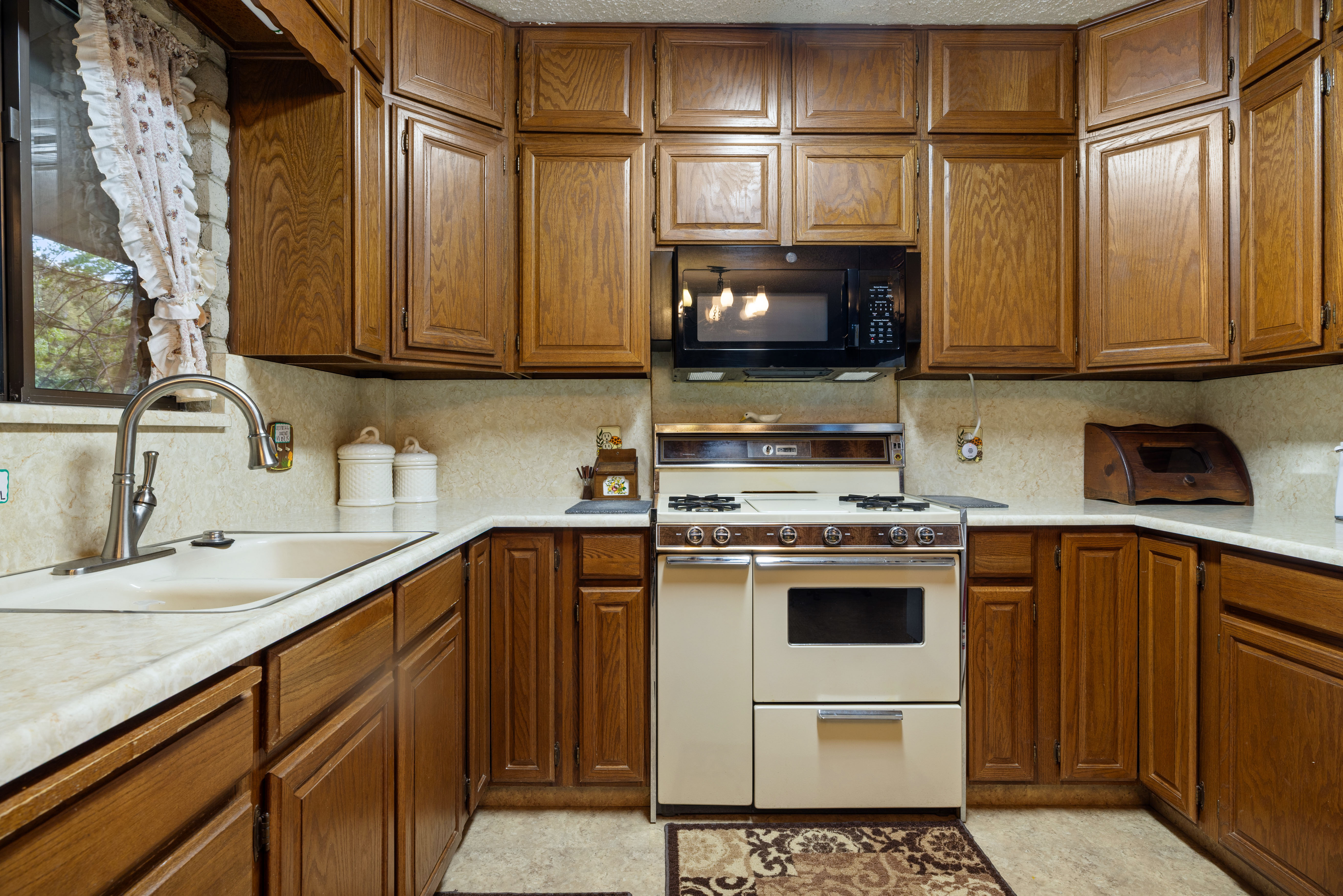 Kitchen featuring wood cabinetry, light-toned countertops, a built-in microwave, and a range with an oven