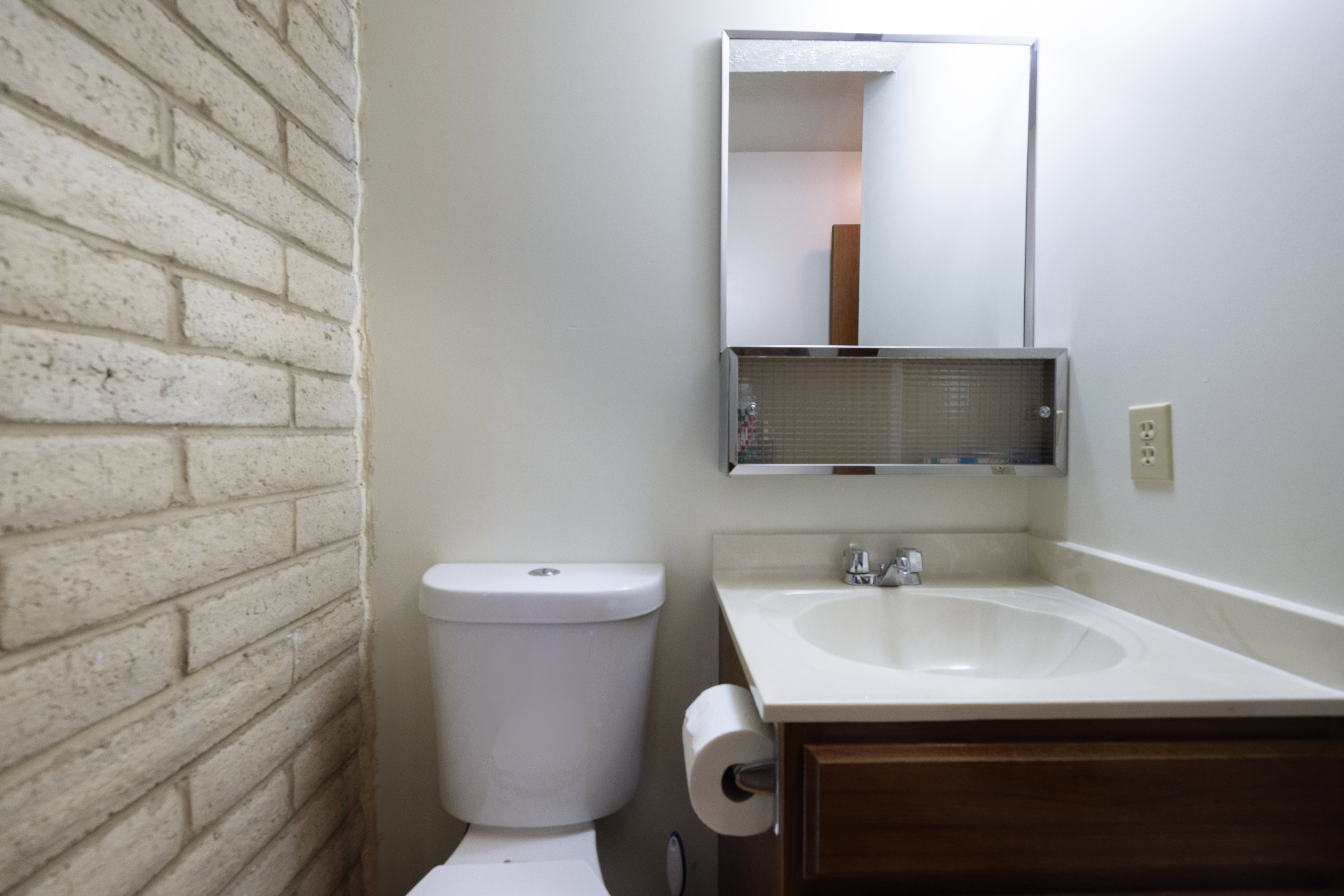 Bathroom featuring a light-colored brick accent wall