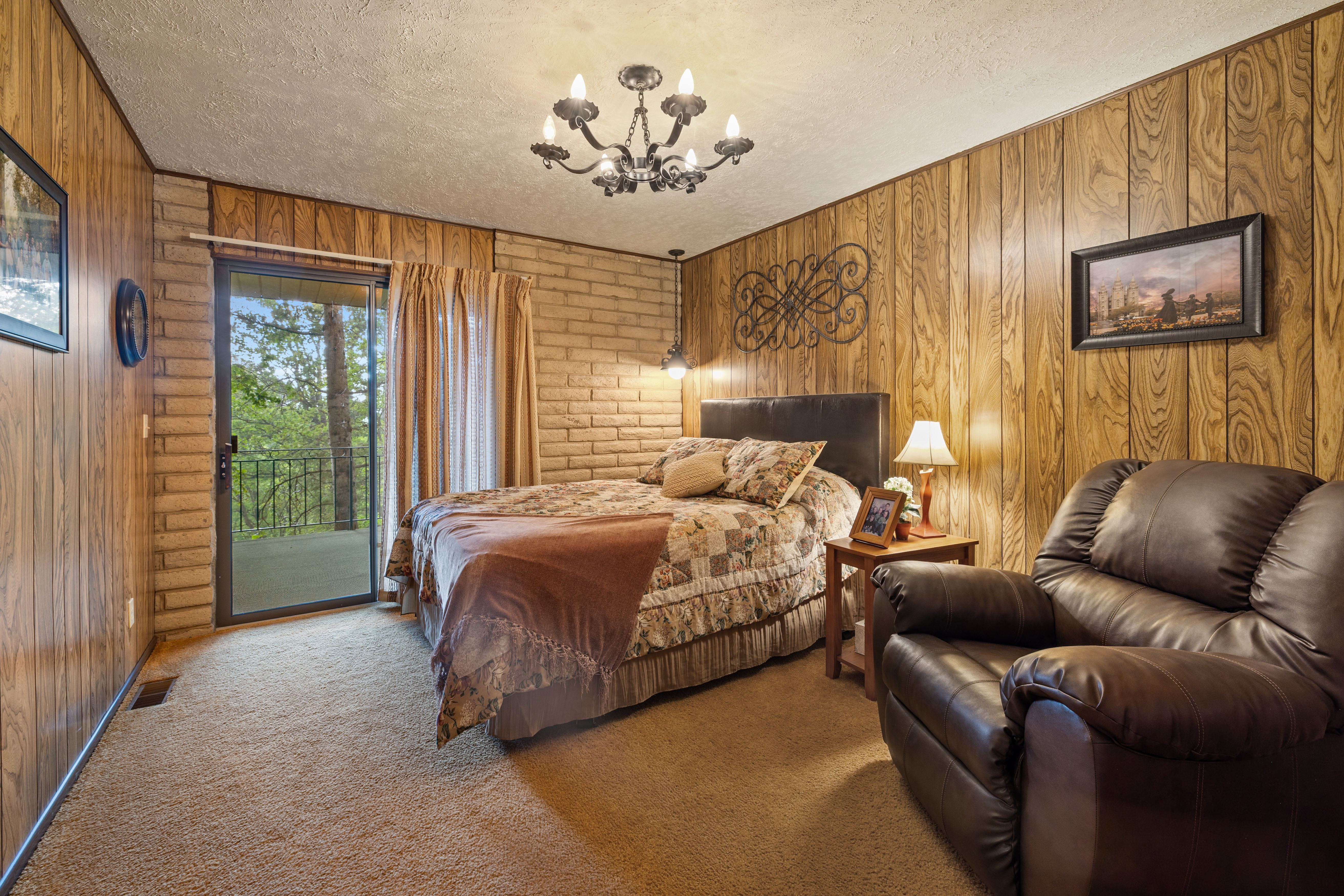 Bedroom featuring wood-paneled walls, a brick accent wall, and textured carpeting