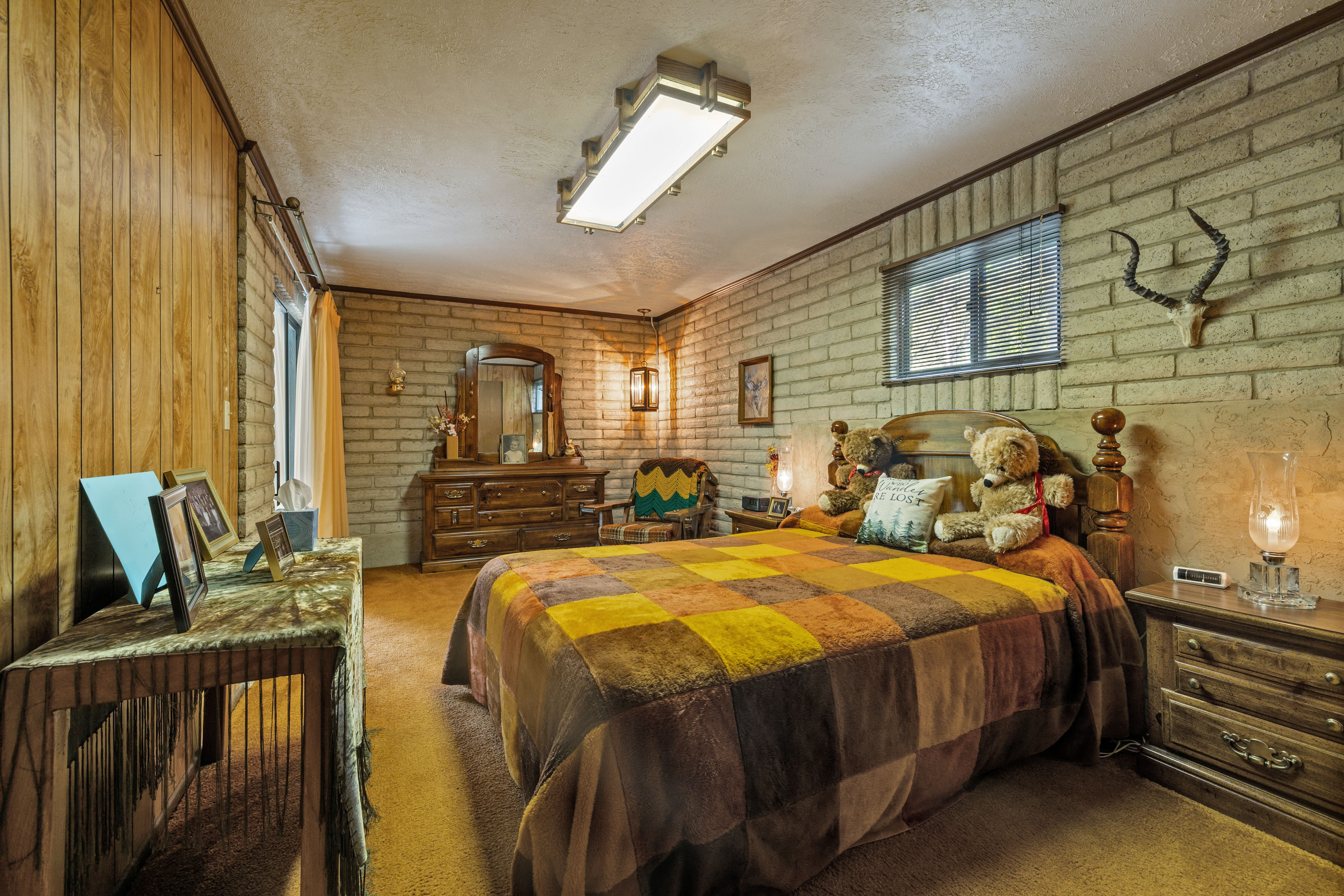 Largest bedroom featuring a paneled wood wall, exposed brick wall, and built-in overhead lighting with an entrance to the covered patio.