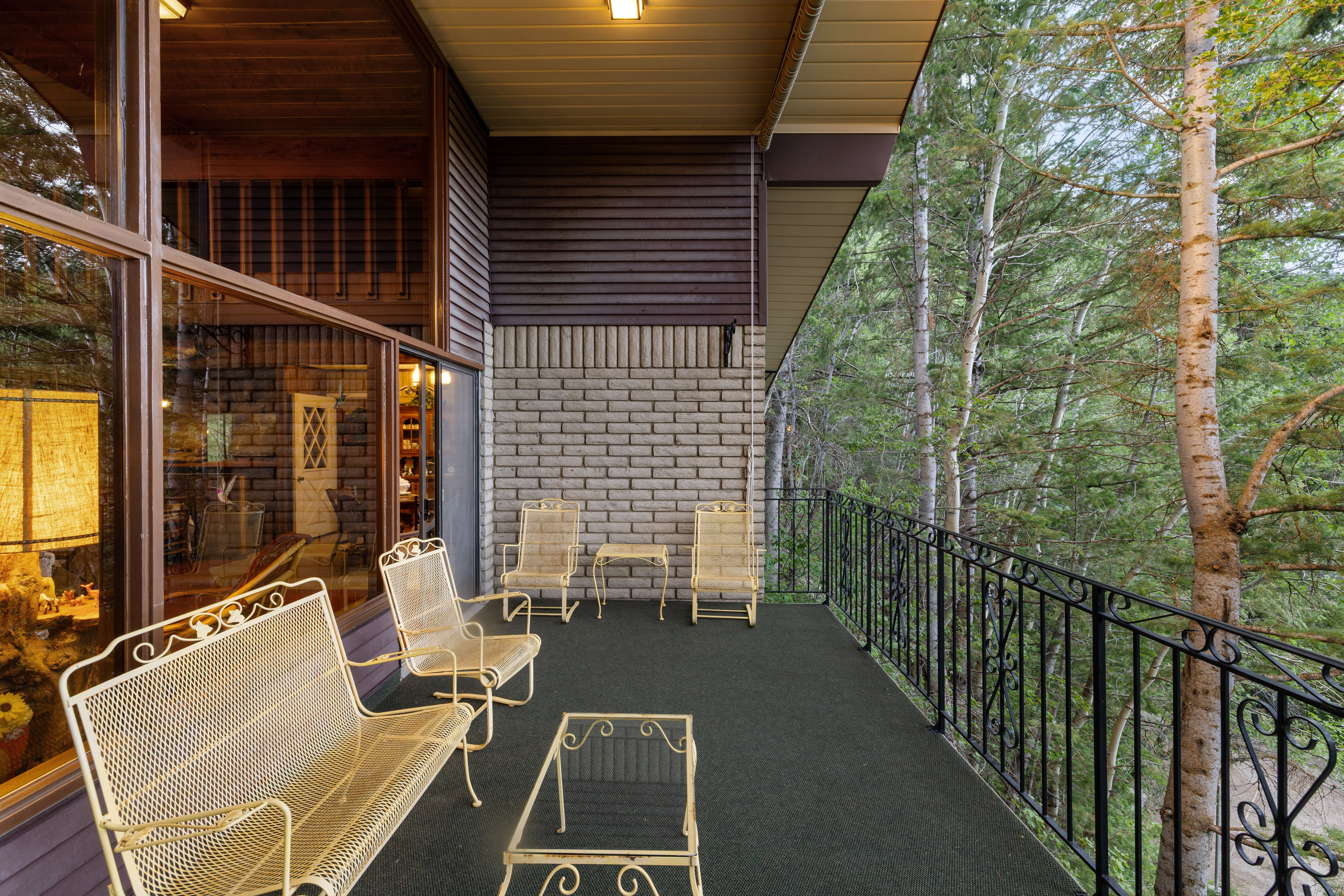 Spacious exterior balcony featuring a dark floor surface, a decorative black metal railing, and a stone accent wall