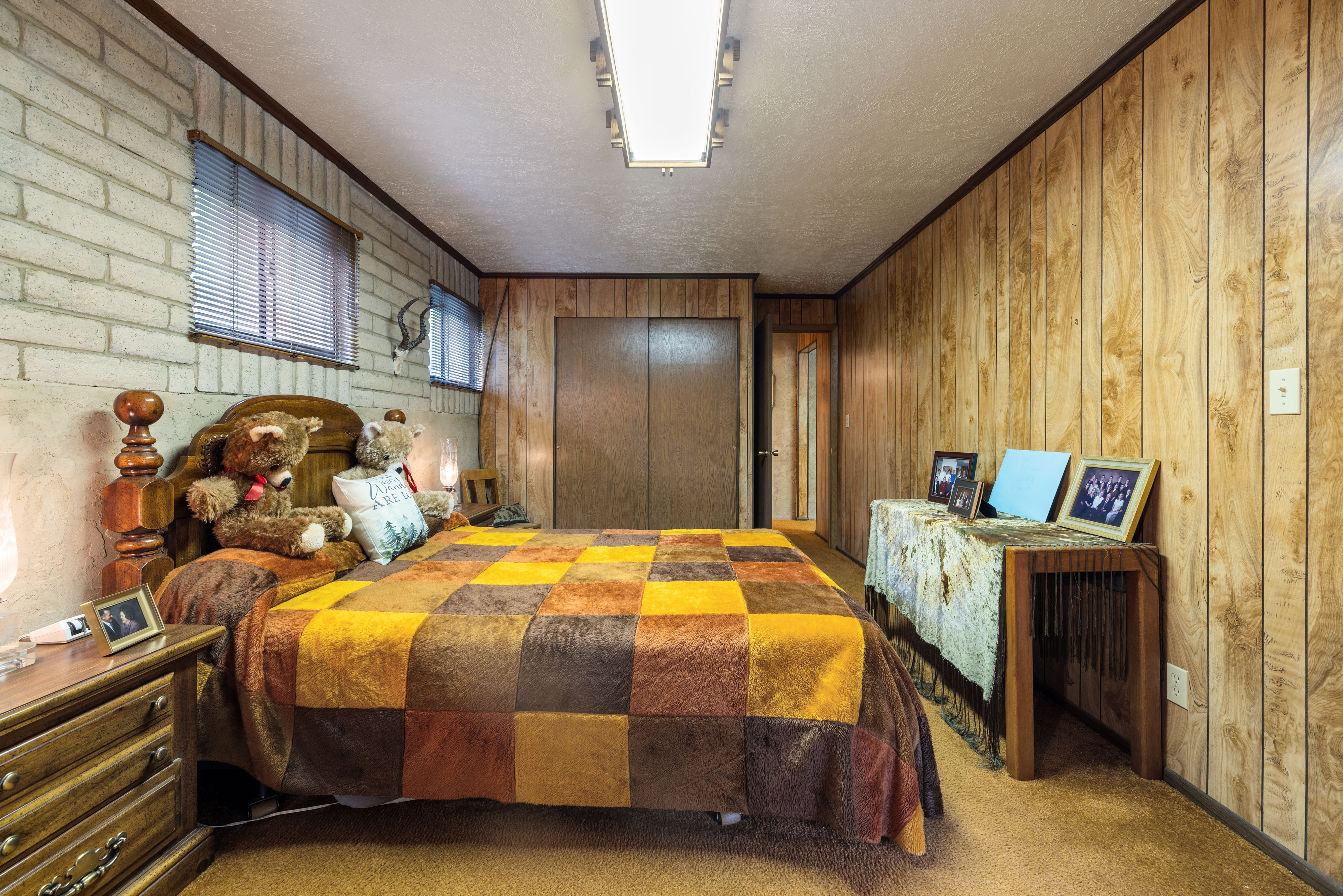 Largest bedroom featuring a wood-finish bed frame, textured wall paneling, and a built-in closet with double doors