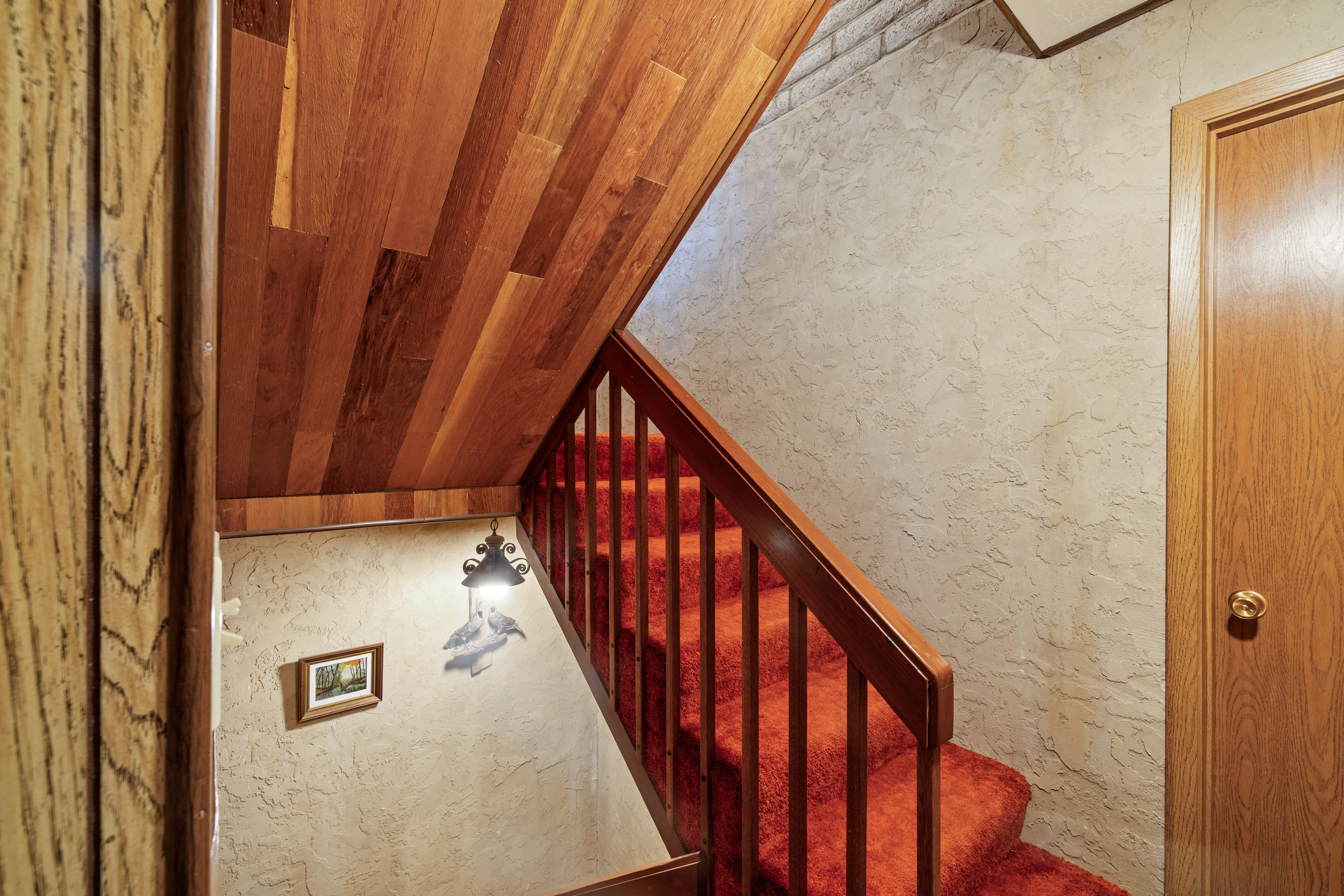 Staircase featuring a wood-finish ceiling, wood railing with balusters, and a textured wall finish