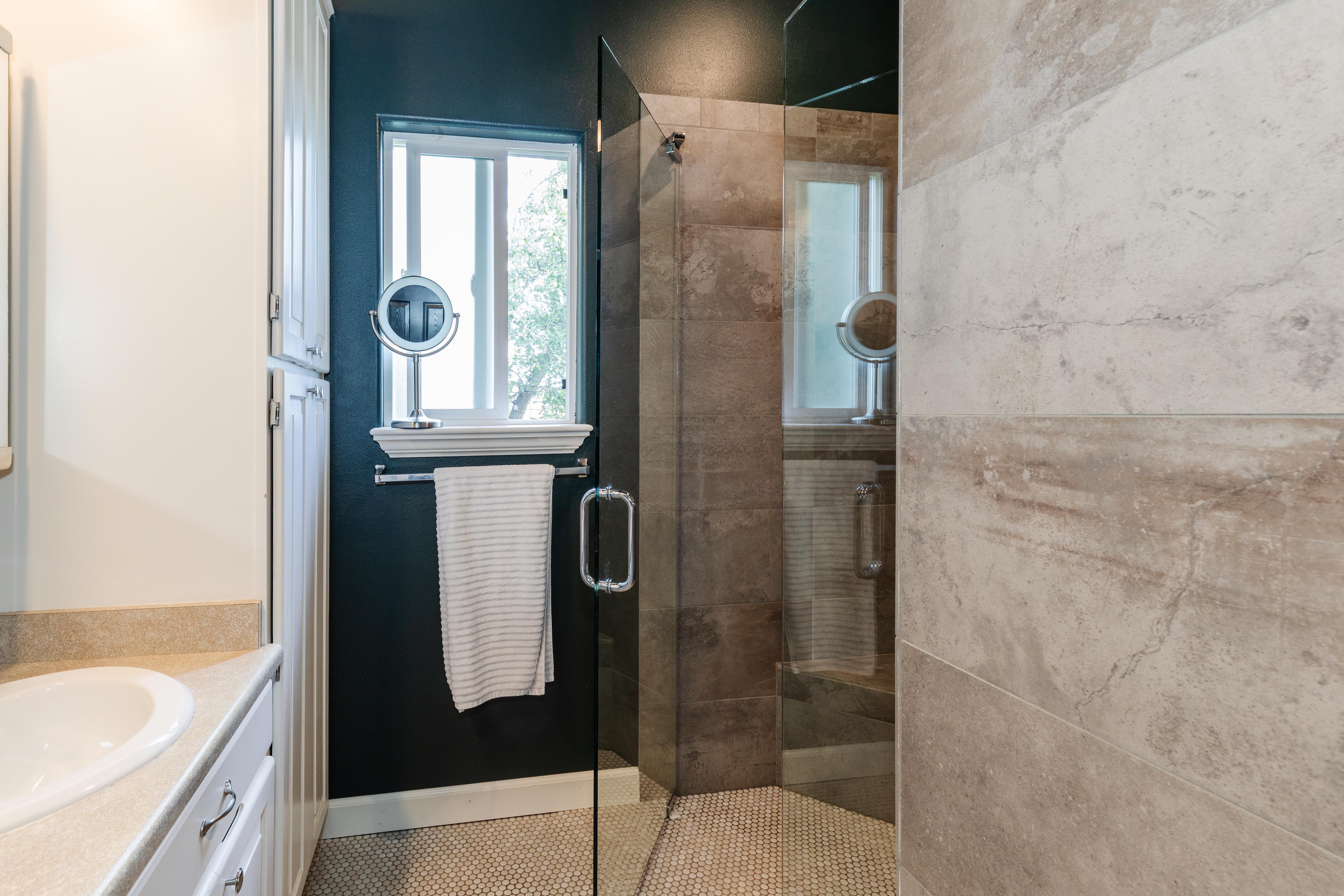 Glass-enclosed shower with a textured tiled surround and a mosaic tile floor