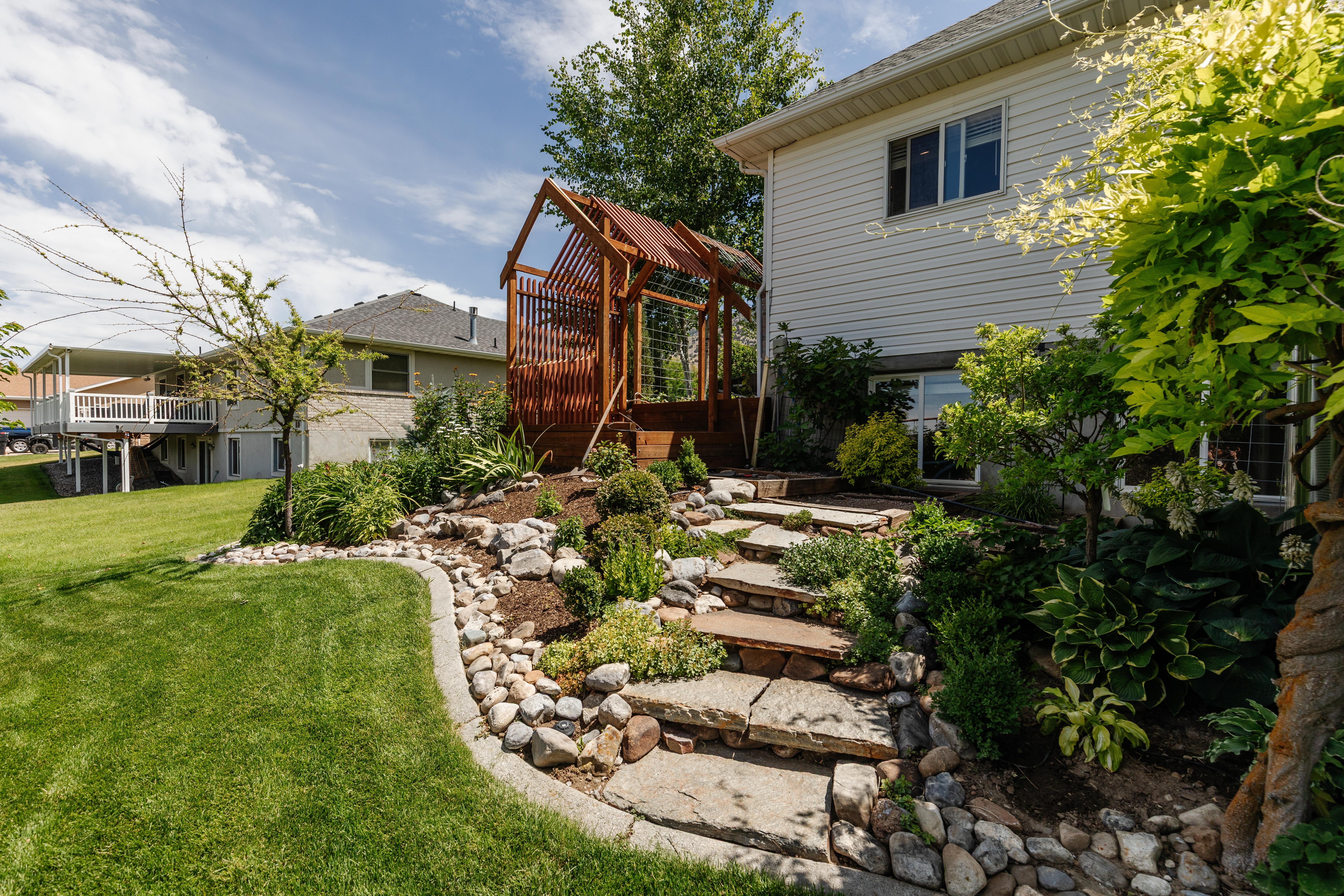 Expansive green lawn with a tiered rock garden featuring flagstone steps
