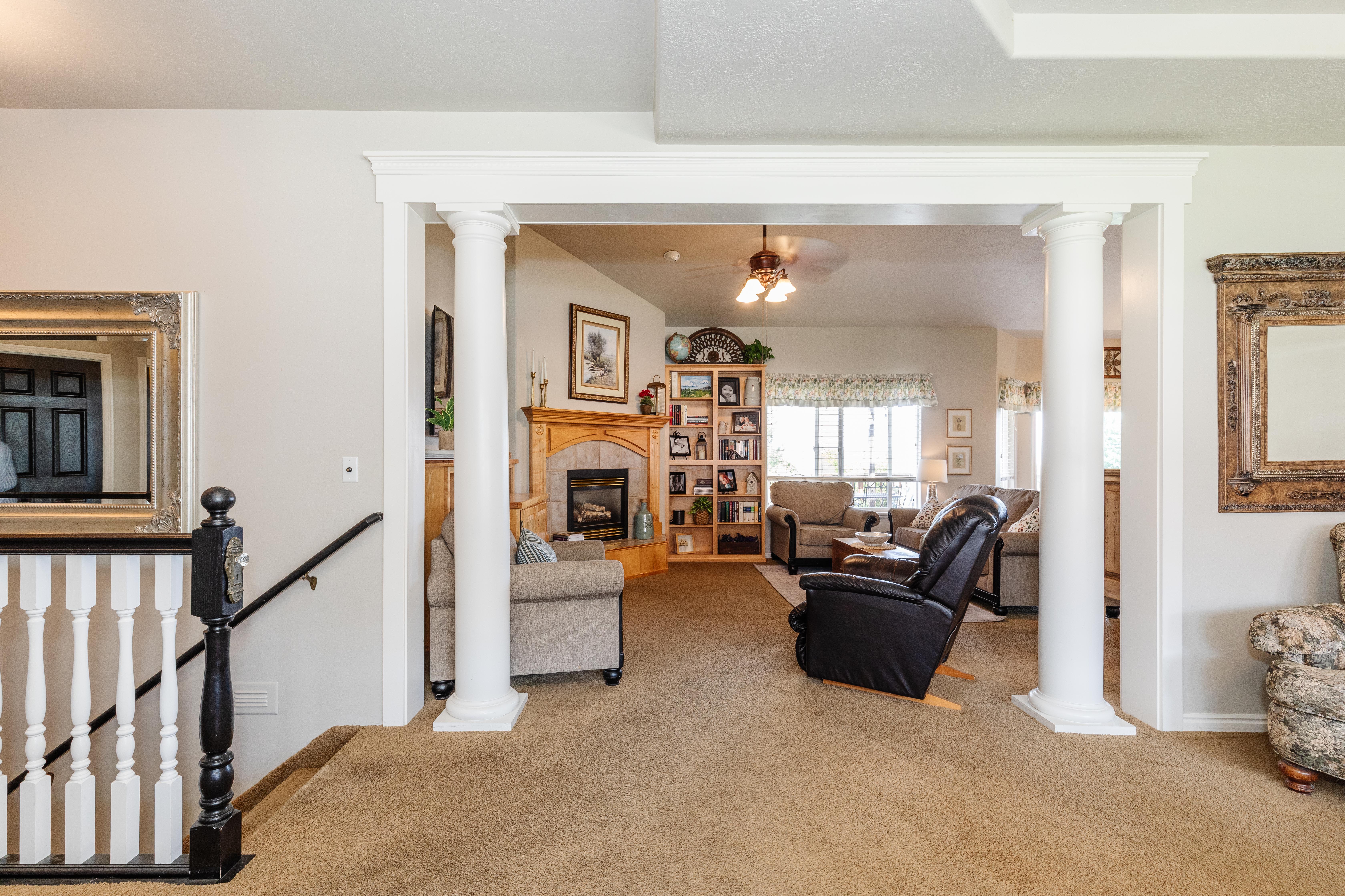 Carpeted living area featuring a decorative archway with columns