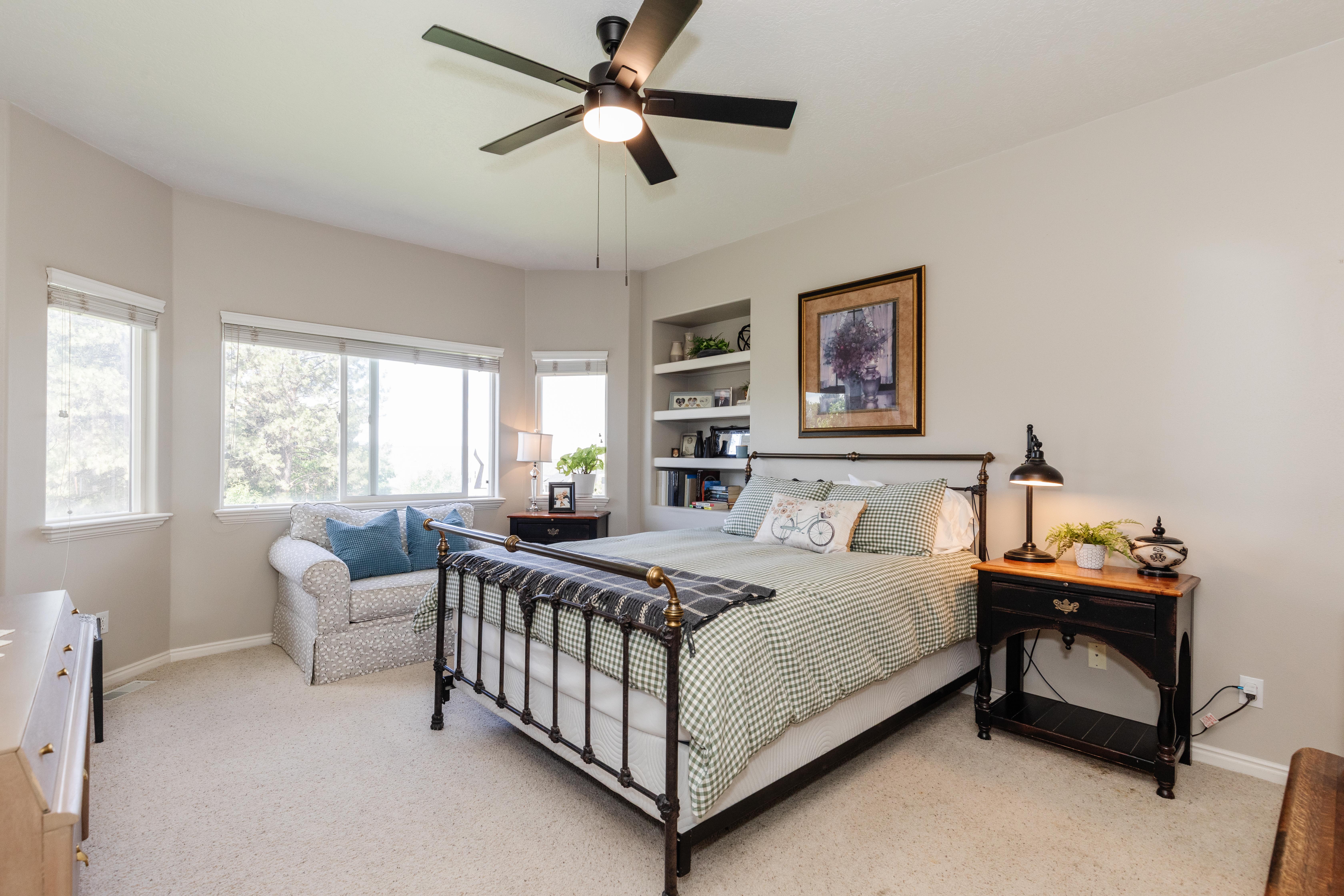 Spacious room featuring multiple windows, a ceiling fan, and built-in shelving