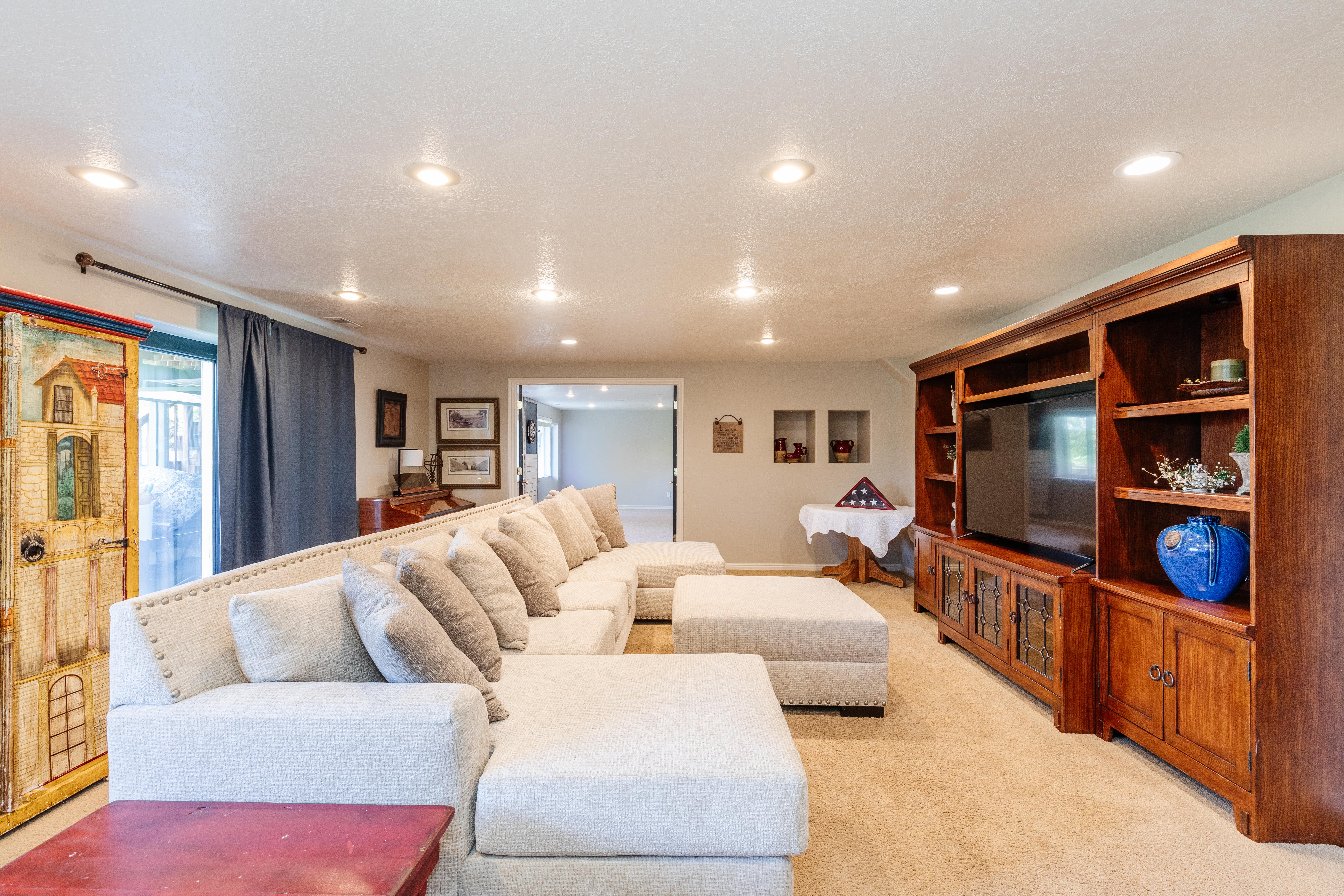 Spacious entertainment room featuring recessed ceiling lighting, a media center with integrated shelving, and carpet flooring