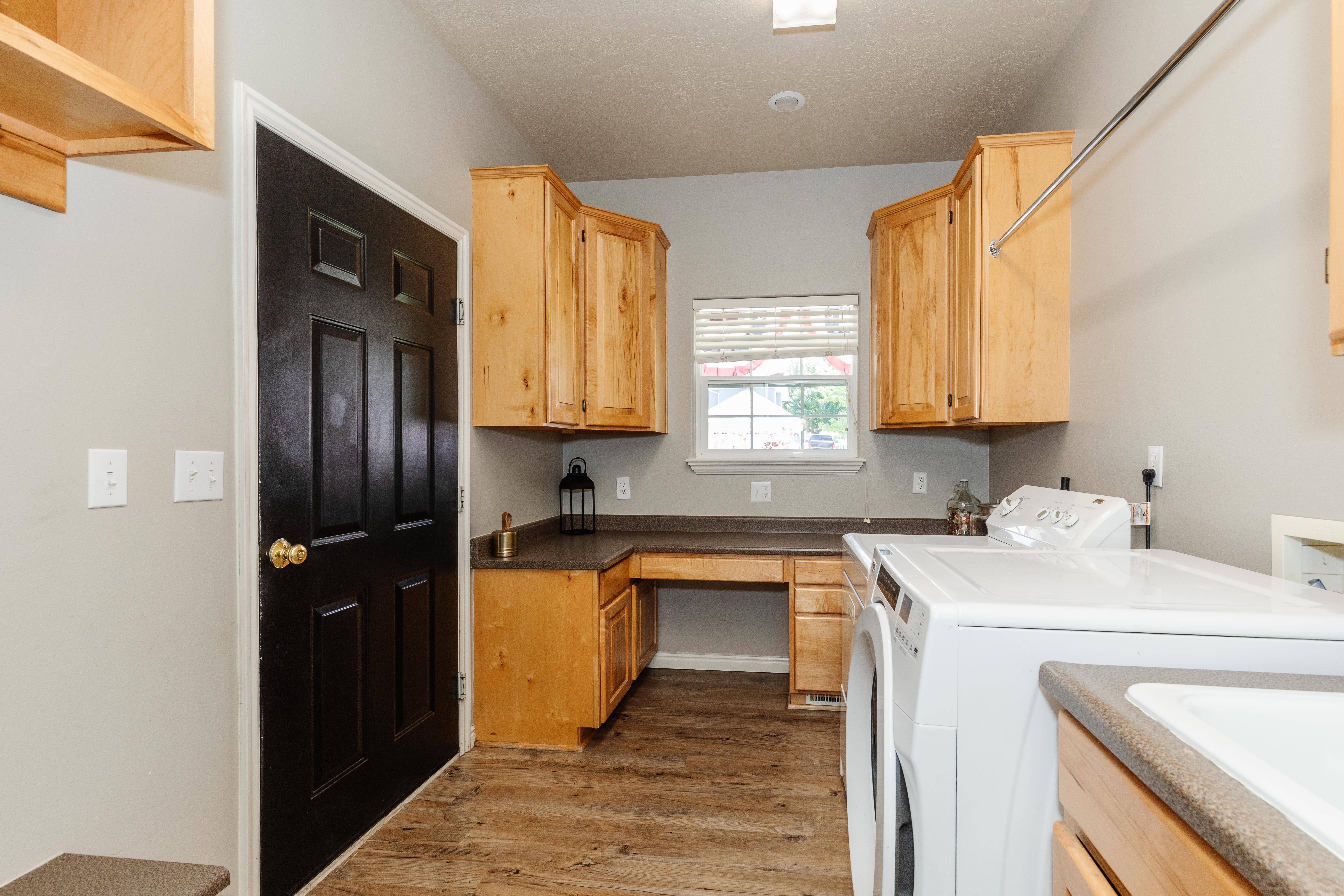 Laundry area featuring wood-finish flooring, light wood cabinetry, and extensive countertop space