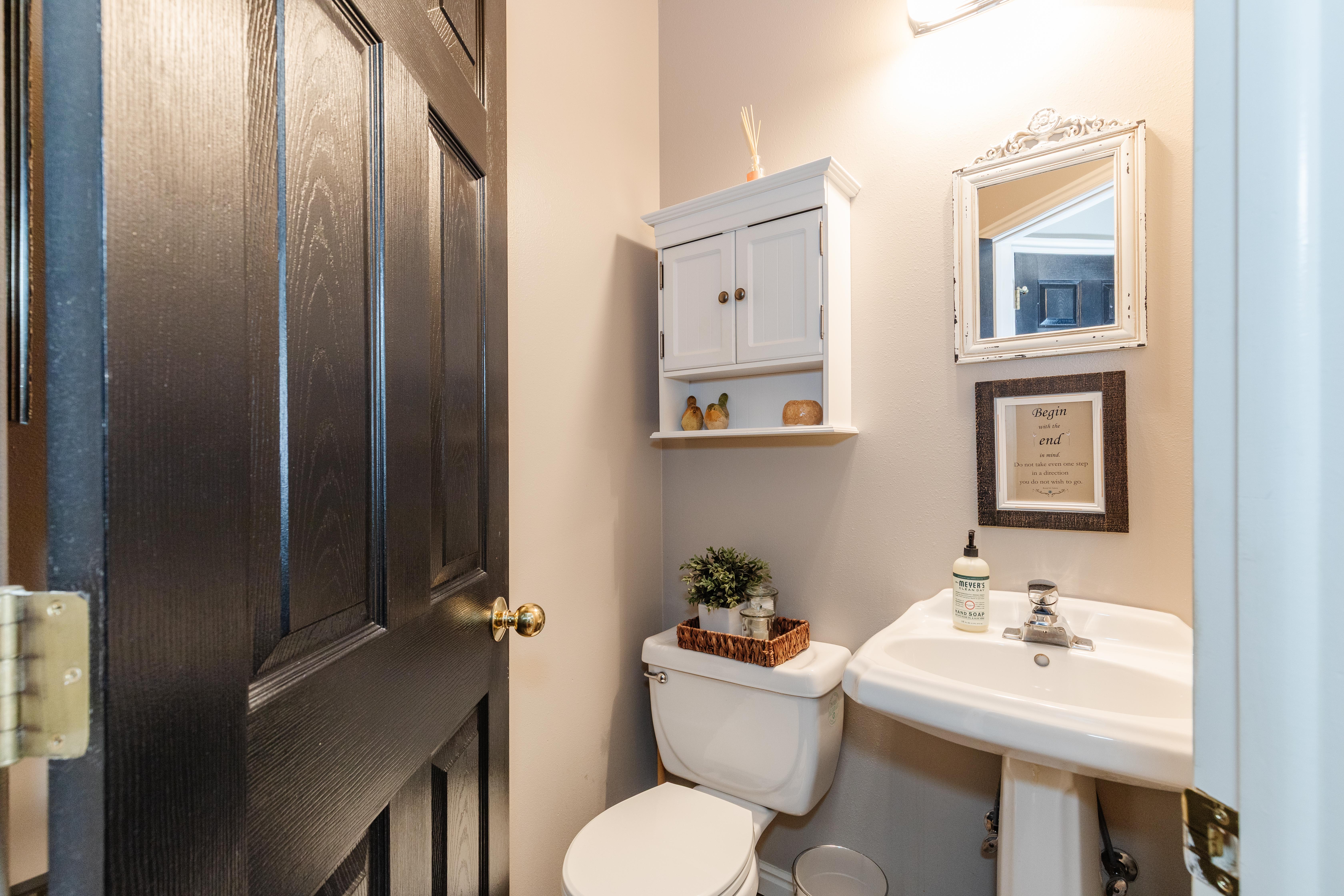 Pedestal sink with chrome faucet, white wall-mounted cabinet, and an ornate framed mirror