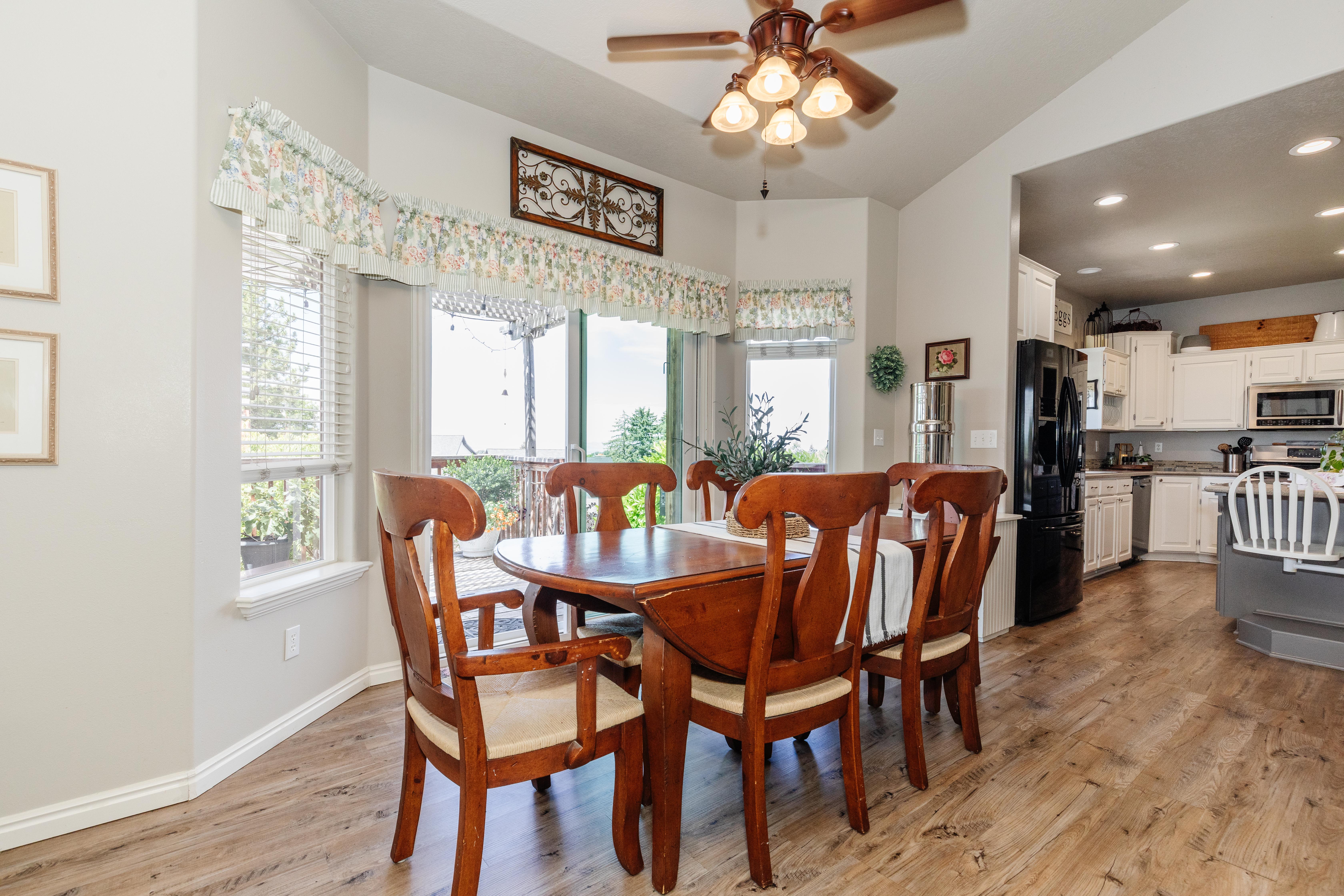 Open-concept dining area featuring wood-finish flooring, a ceiling fan with integrated lighting, and direct access to an outdoor deck