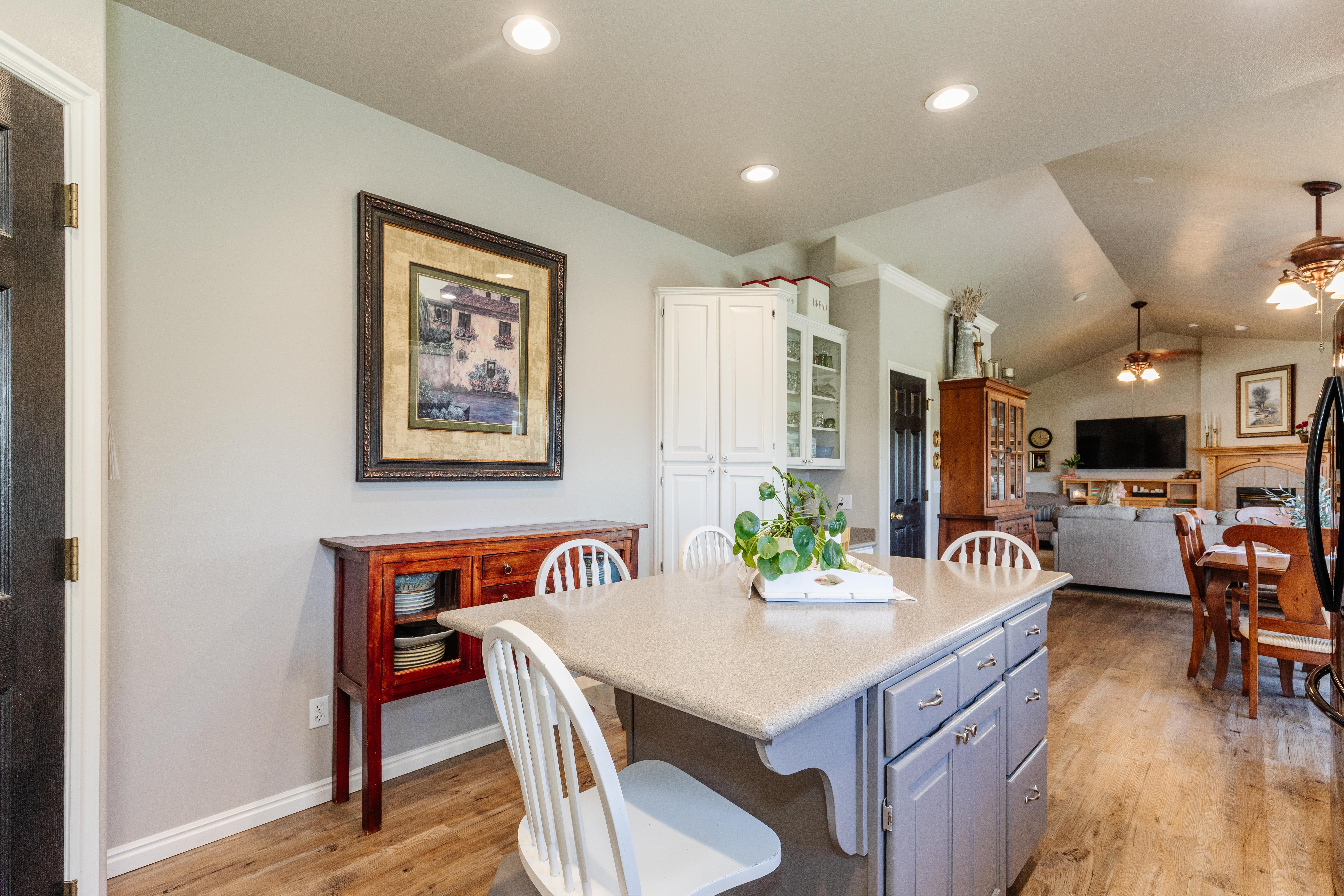 Kitchen island with seating for three, featuring a light countertop and gray cabinetry
