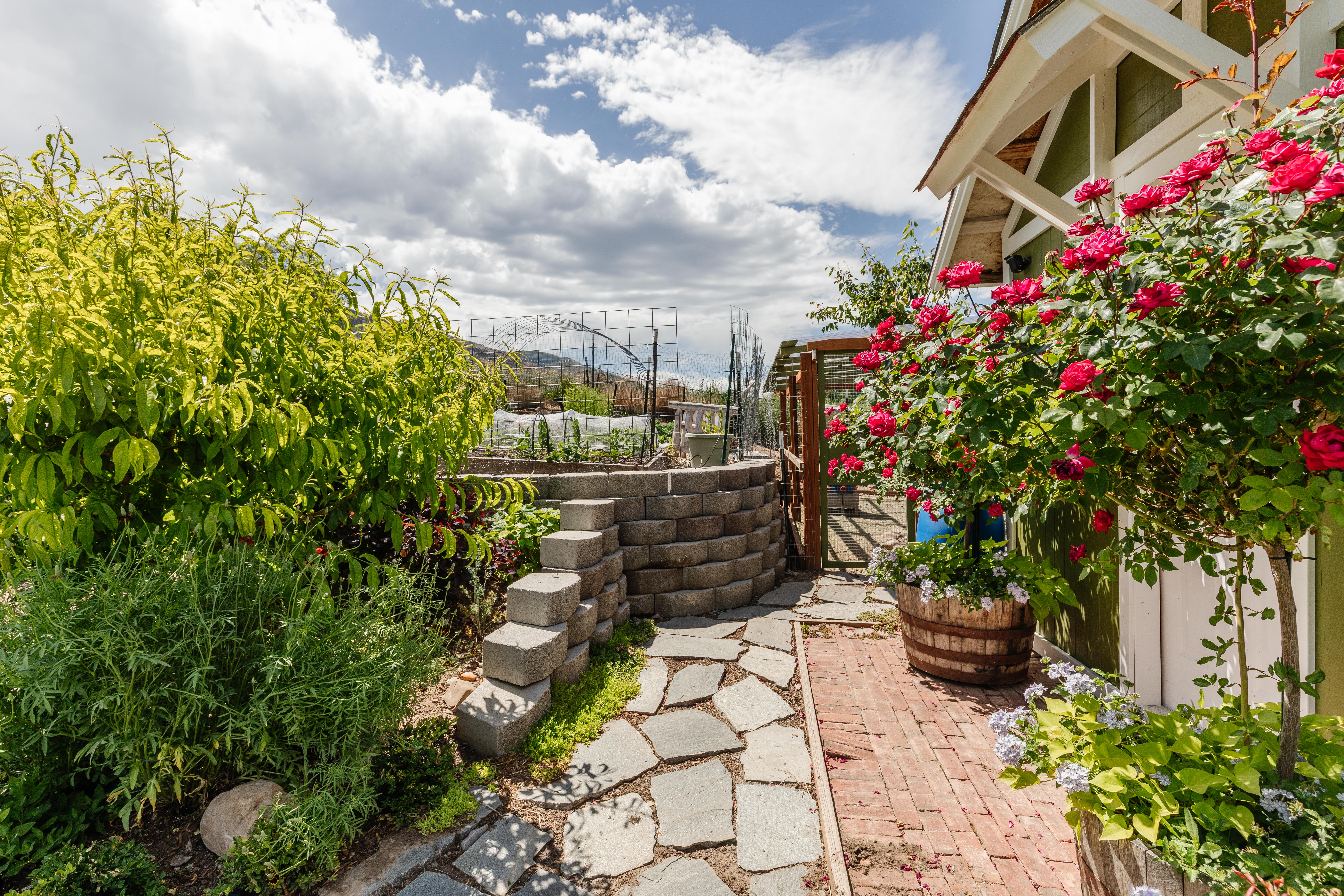 Manicured outdoor space featuring a flagstone pathway, a brick border, and mature rose bushes