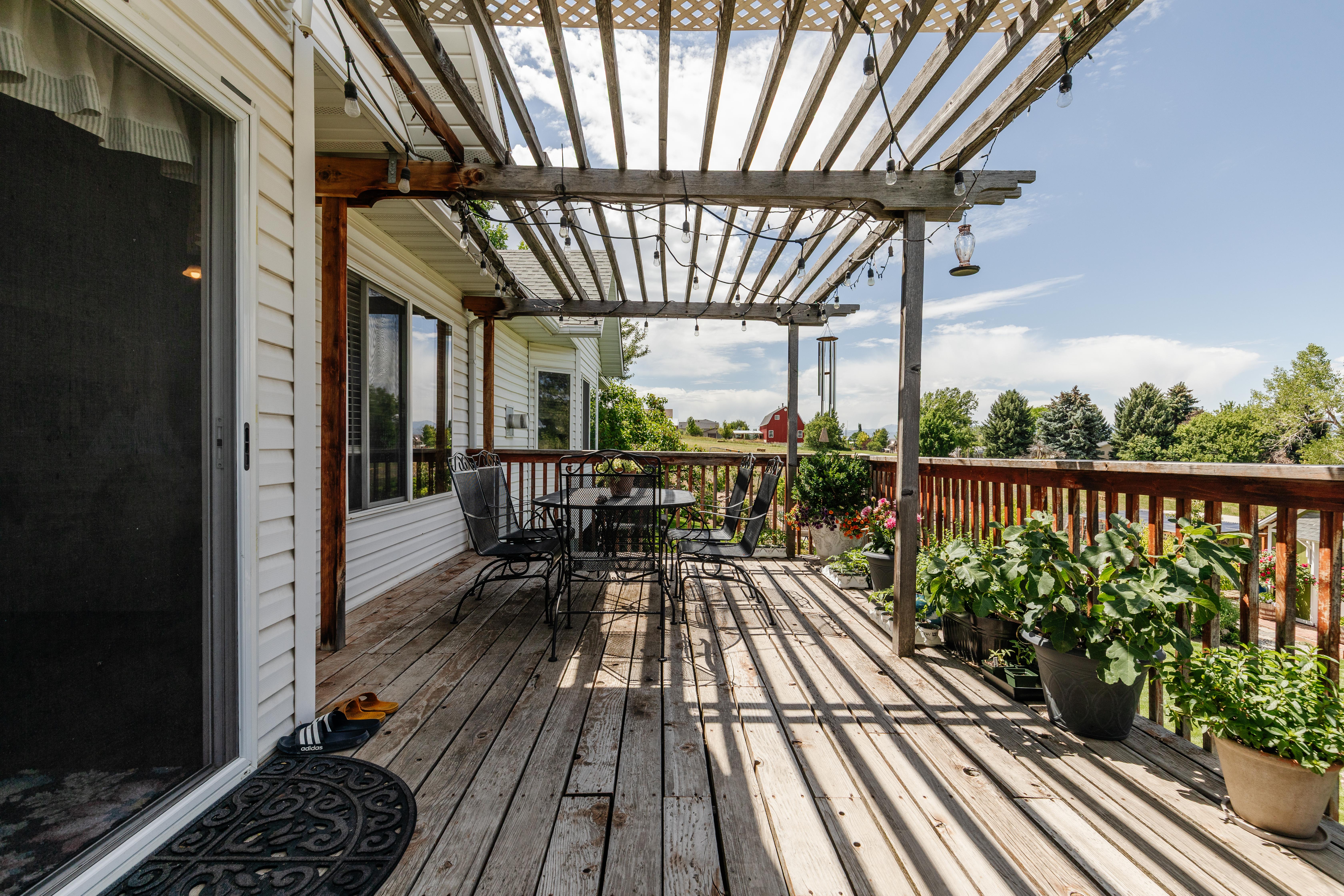 Expansive wooden deck featuring a slatted pergola overhead