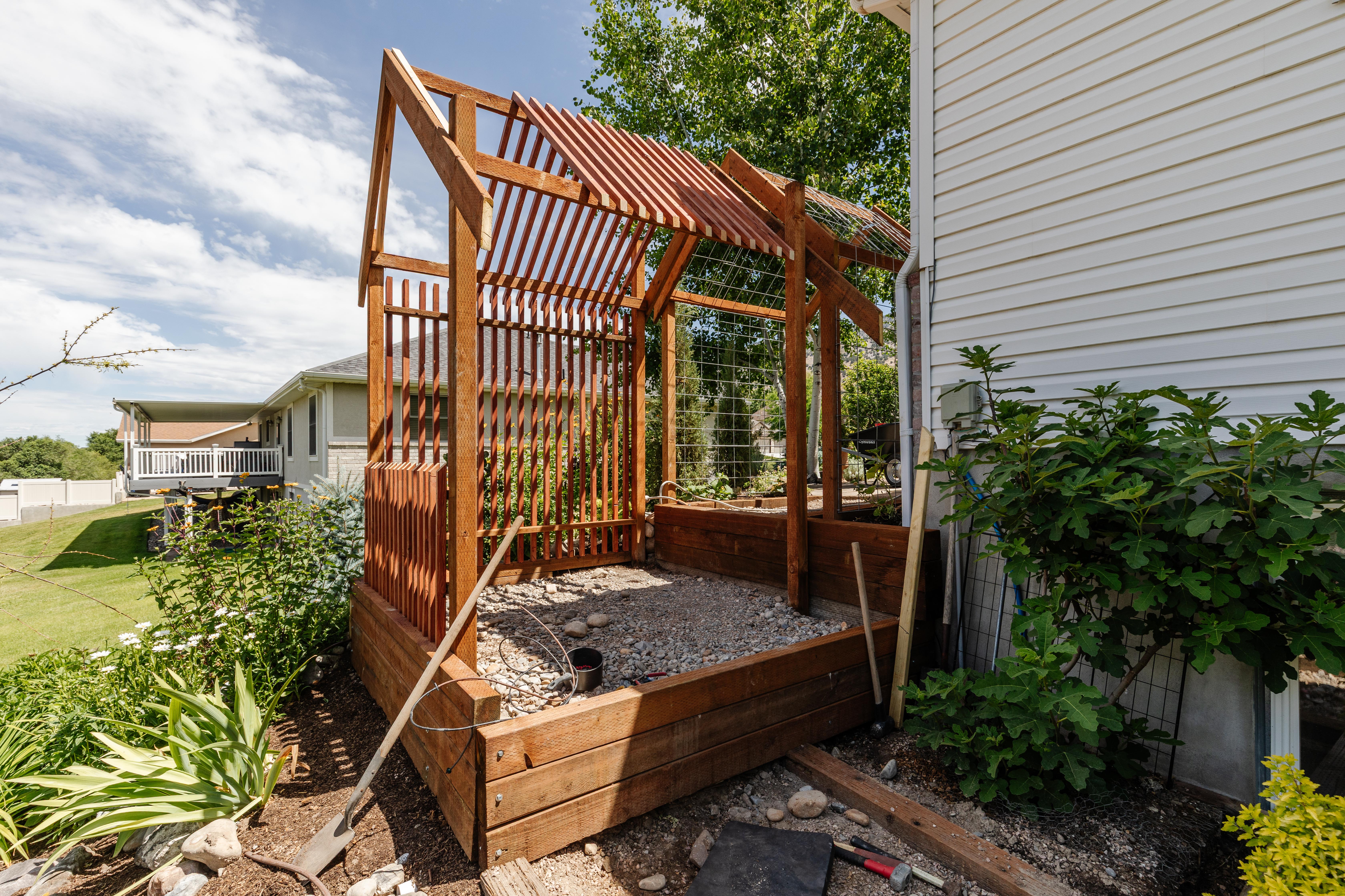 Custom-built garden structure featuring wood-finish framing, slatted roofing, and integrated wire mesh panels